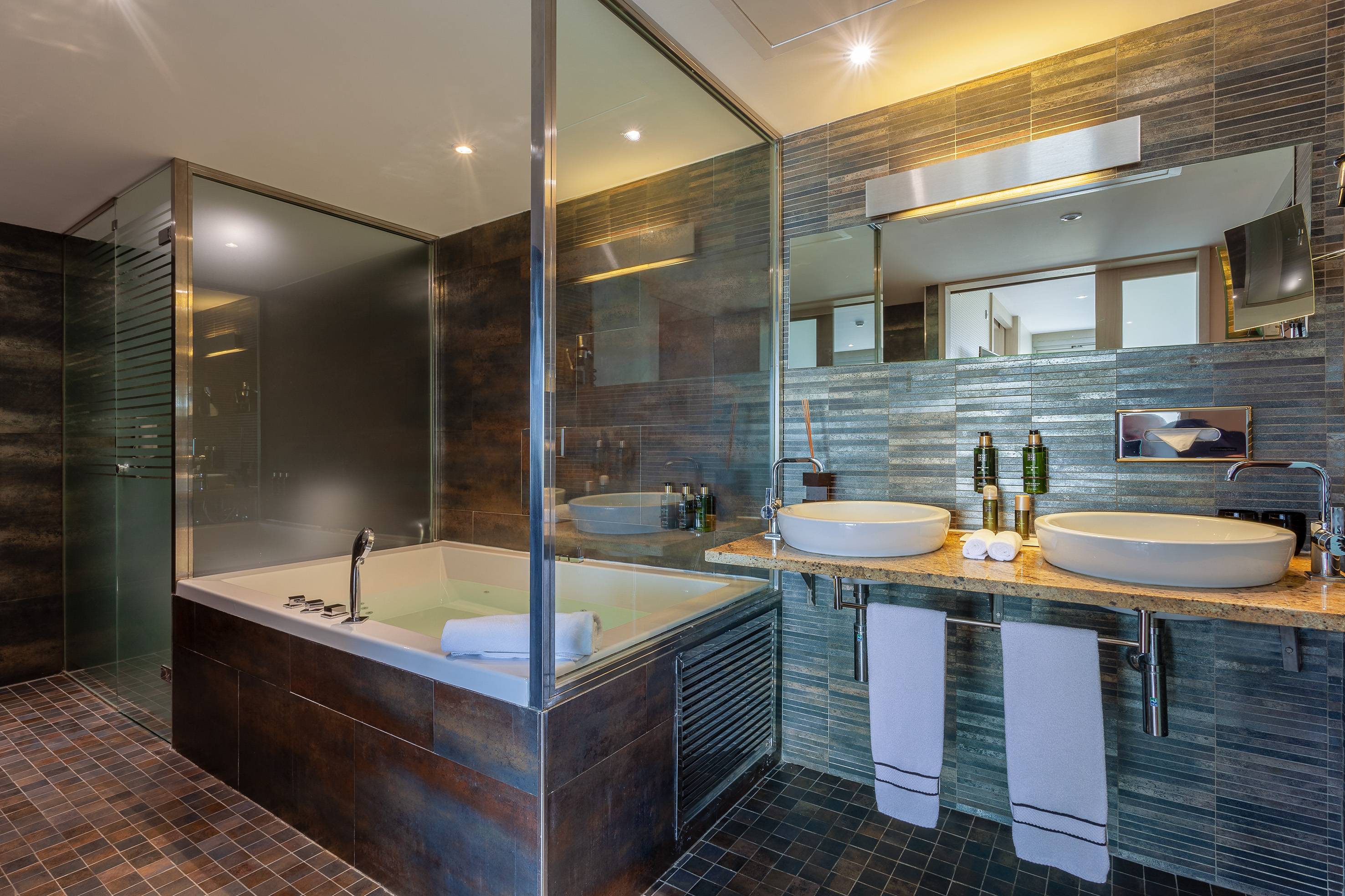 Stylish bathroom featuring jetted tub, glass shower, and double basin vanity.