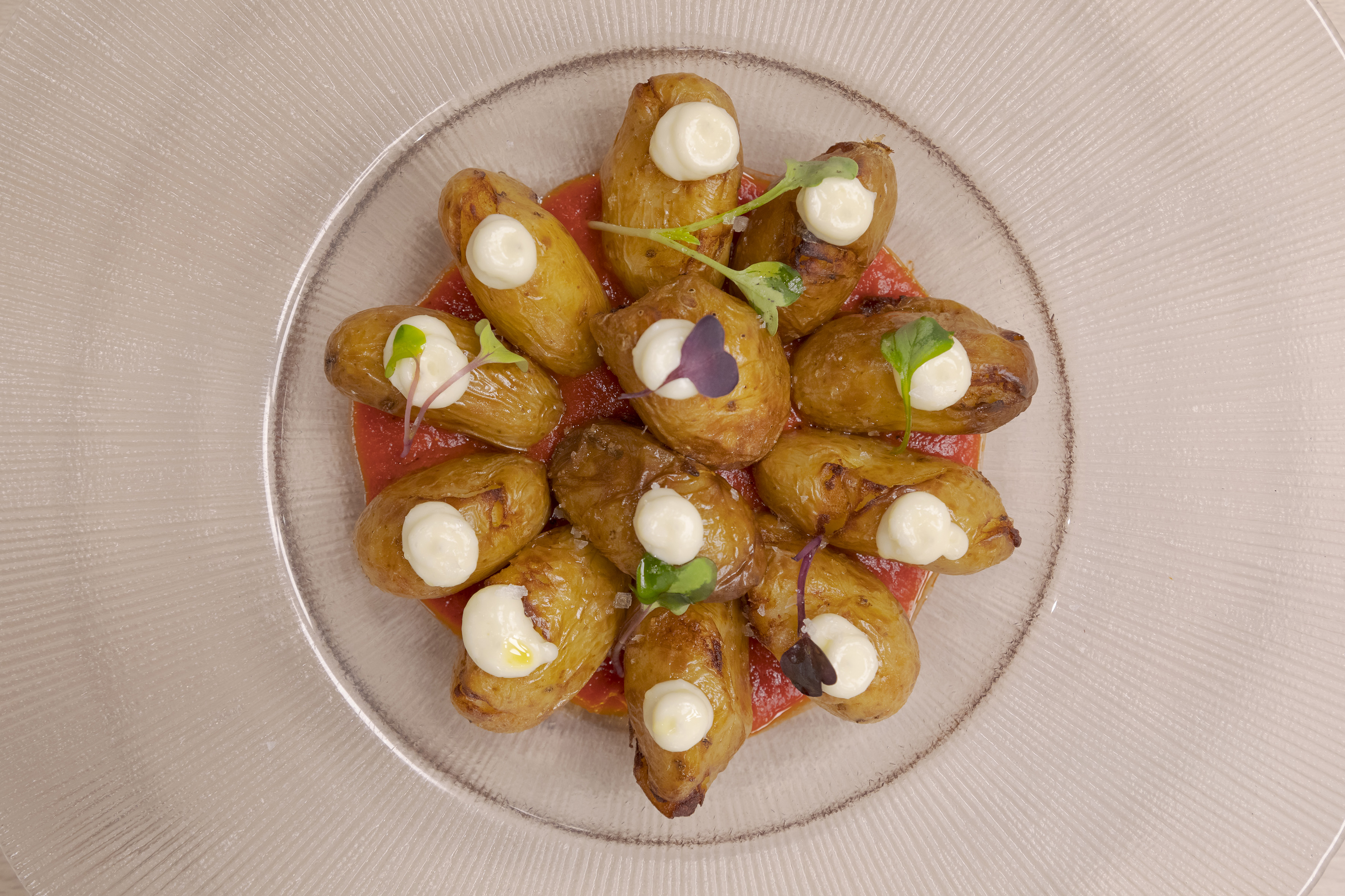 Gourmet roasted baby potatoes with aioli, red sauce, and fresh microgreens.