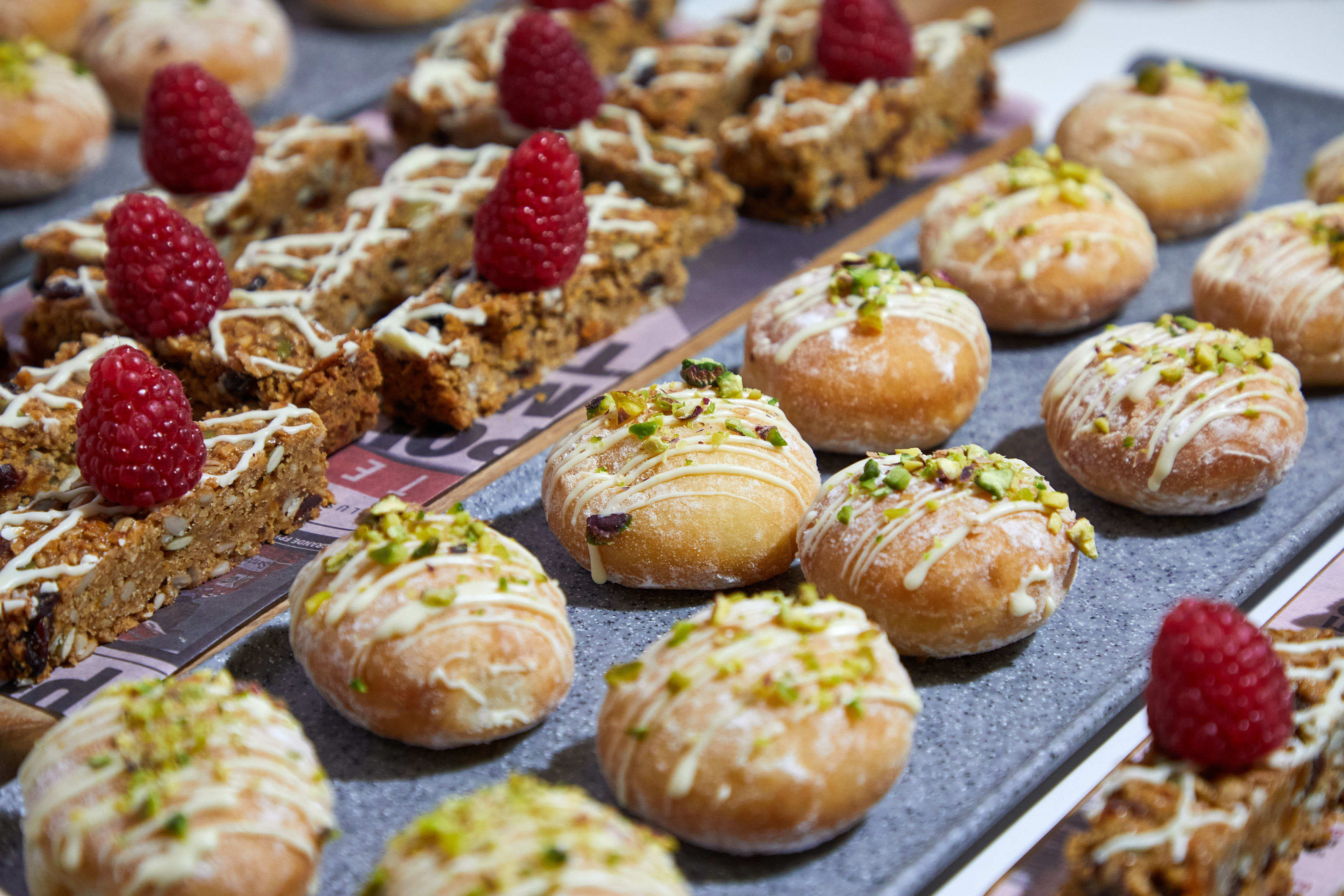 Baked goods: Pistachio doughnuts with white drizzle and raspberry-topped oat bars.