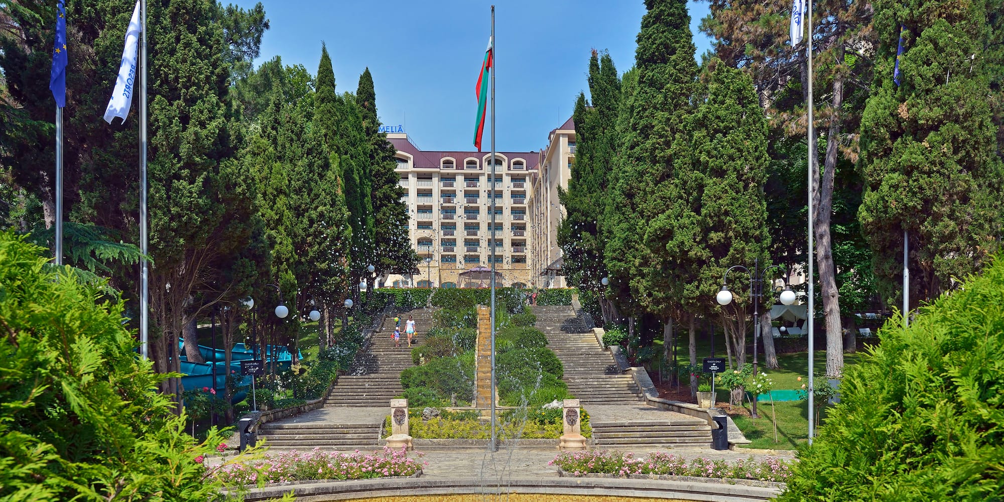 a fountain in a park with trees and a building in the background