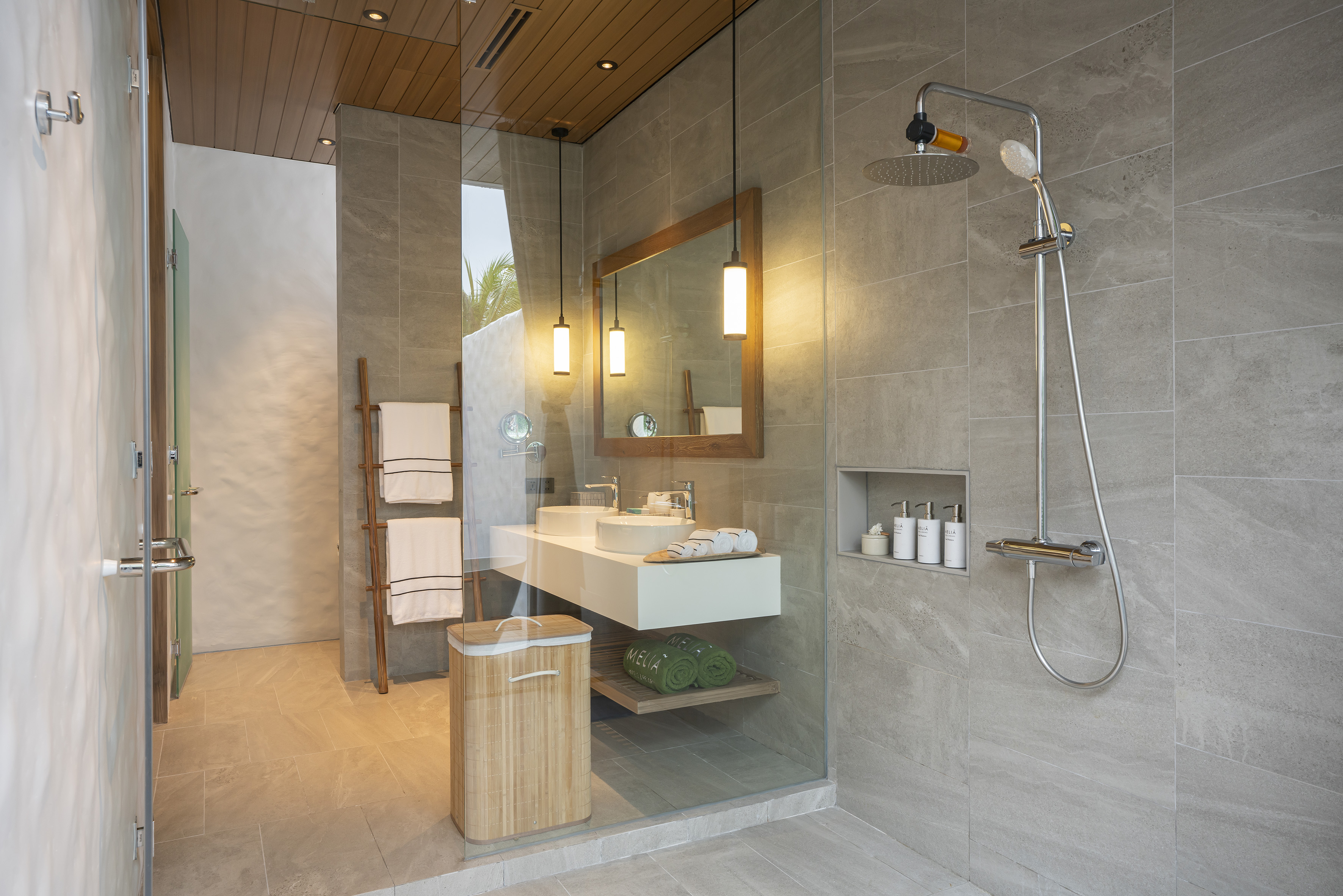 Sleek modern bathroom with glass shower, double vanity, and grey tiles.