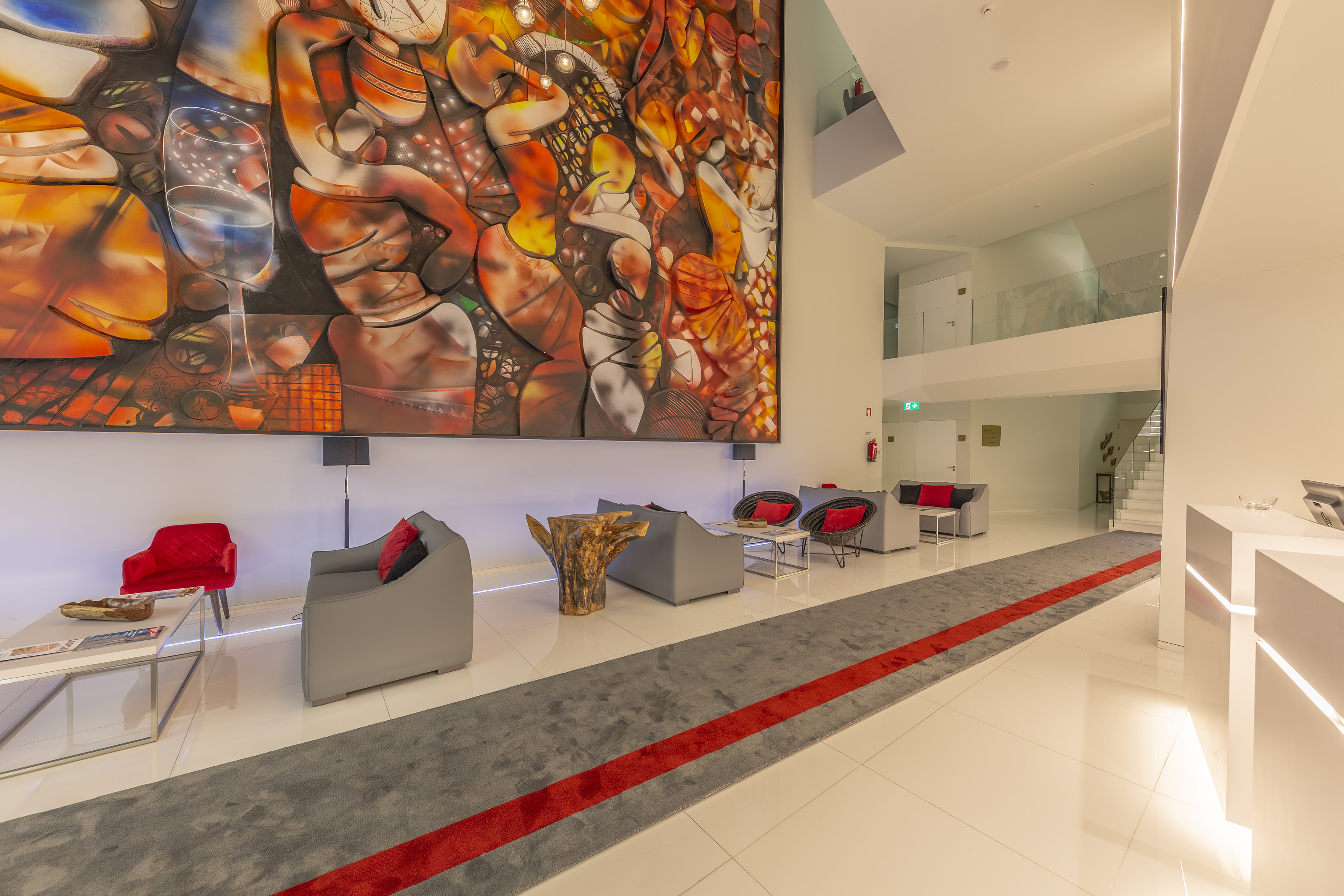 Modern hotel lobby with a large colorful abstract wall mural and grey lounge seating.