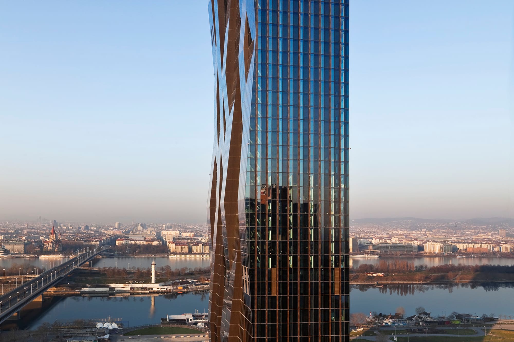 Contemporary skyscraper with patterned glass facade overlooking city and river.