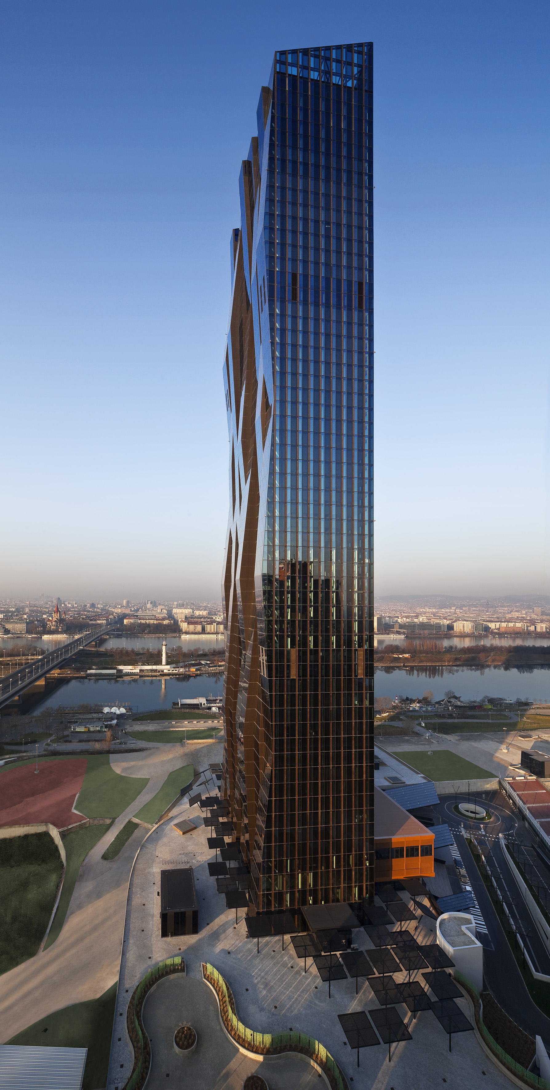 Contemporary skyscraper with patterned glass facade overlooking city and river.