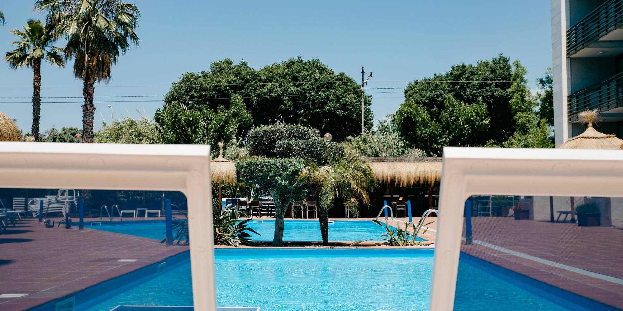 a pool with chairs and trees in the background