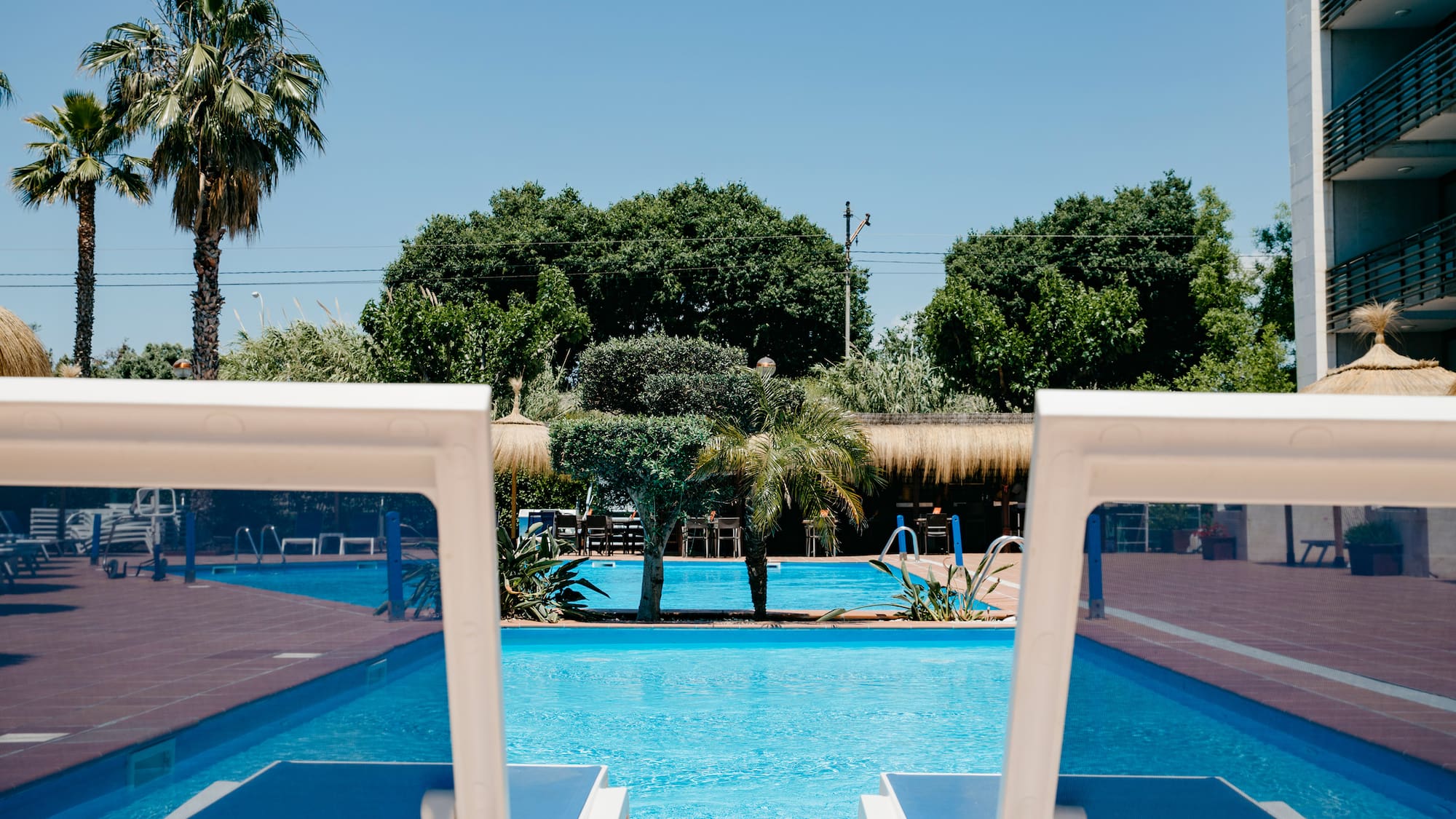 a pool with chairs and trees in the background