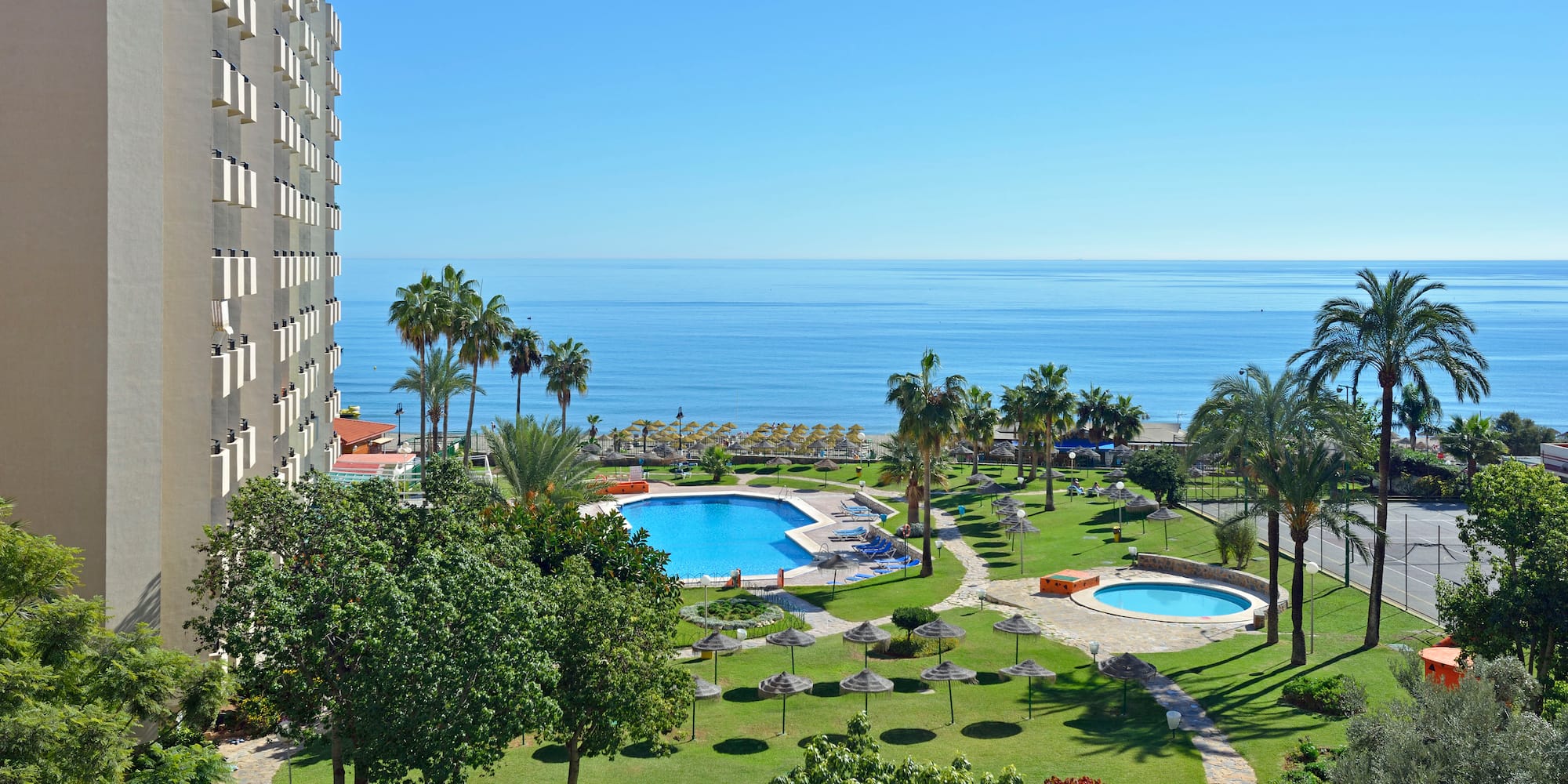 a pool in a resort with a large body of water