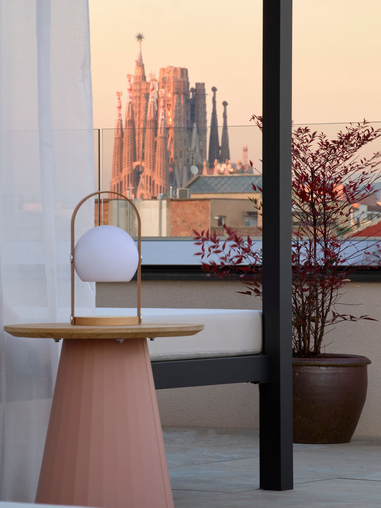 Rooftop terrace with modern lamp, Sagrada Familia view, Barcelona sunset.