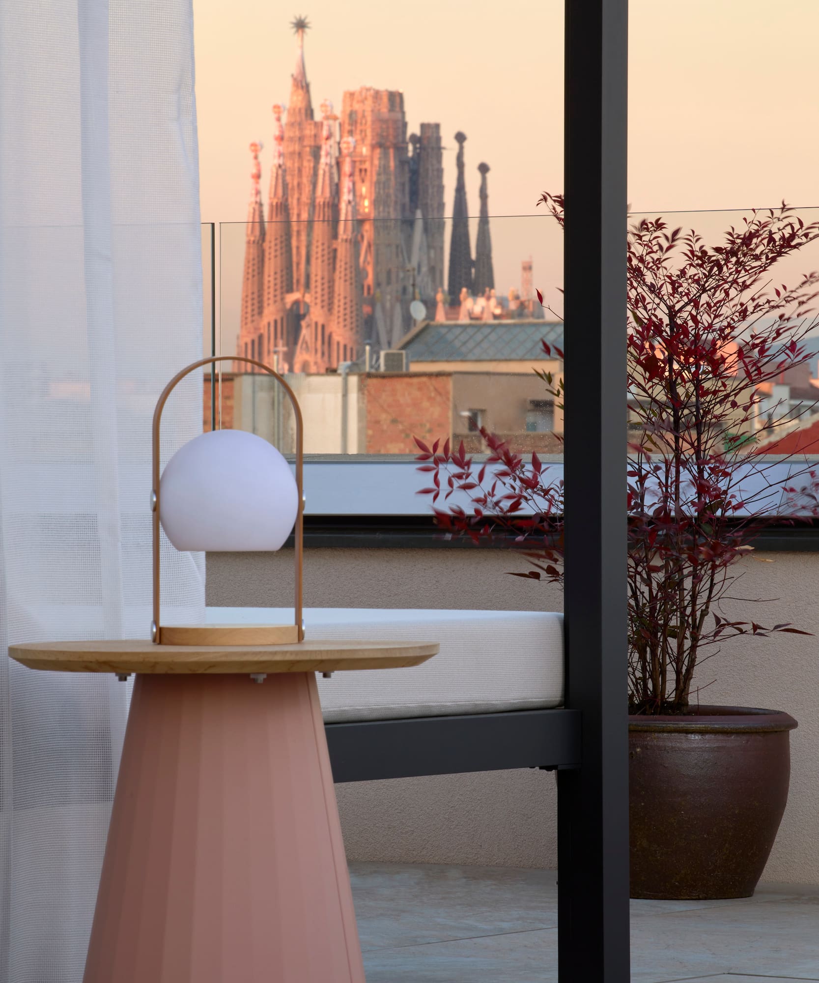 Rooftop terrace with modern lamp, Sagrada Familia view, Barcelona sunset.