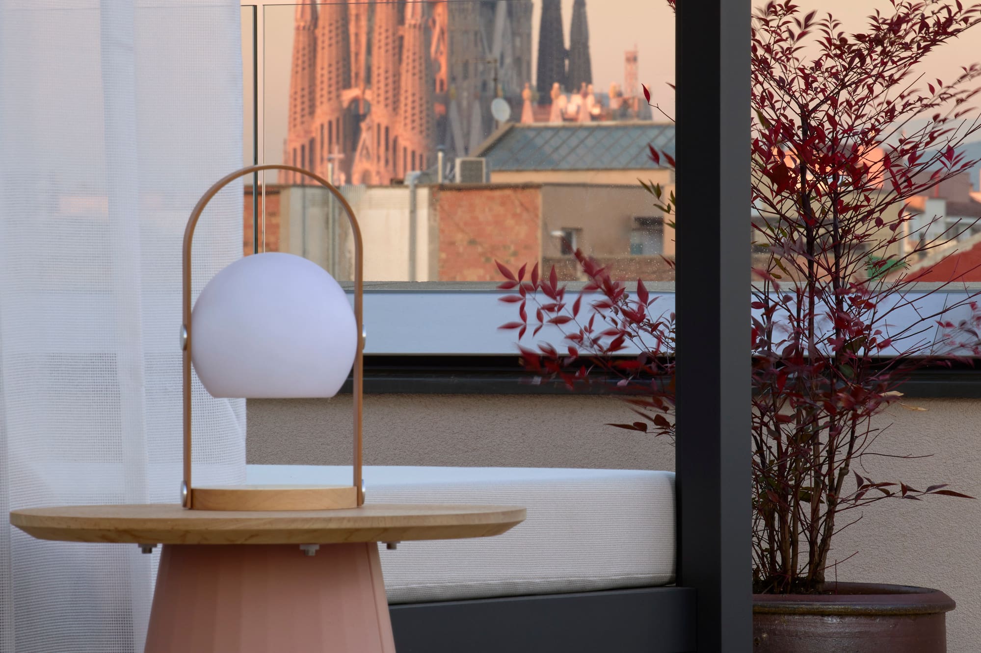 Rooftop terrace with modern lamp, Sagrada Familia view, Barcelona sunset.