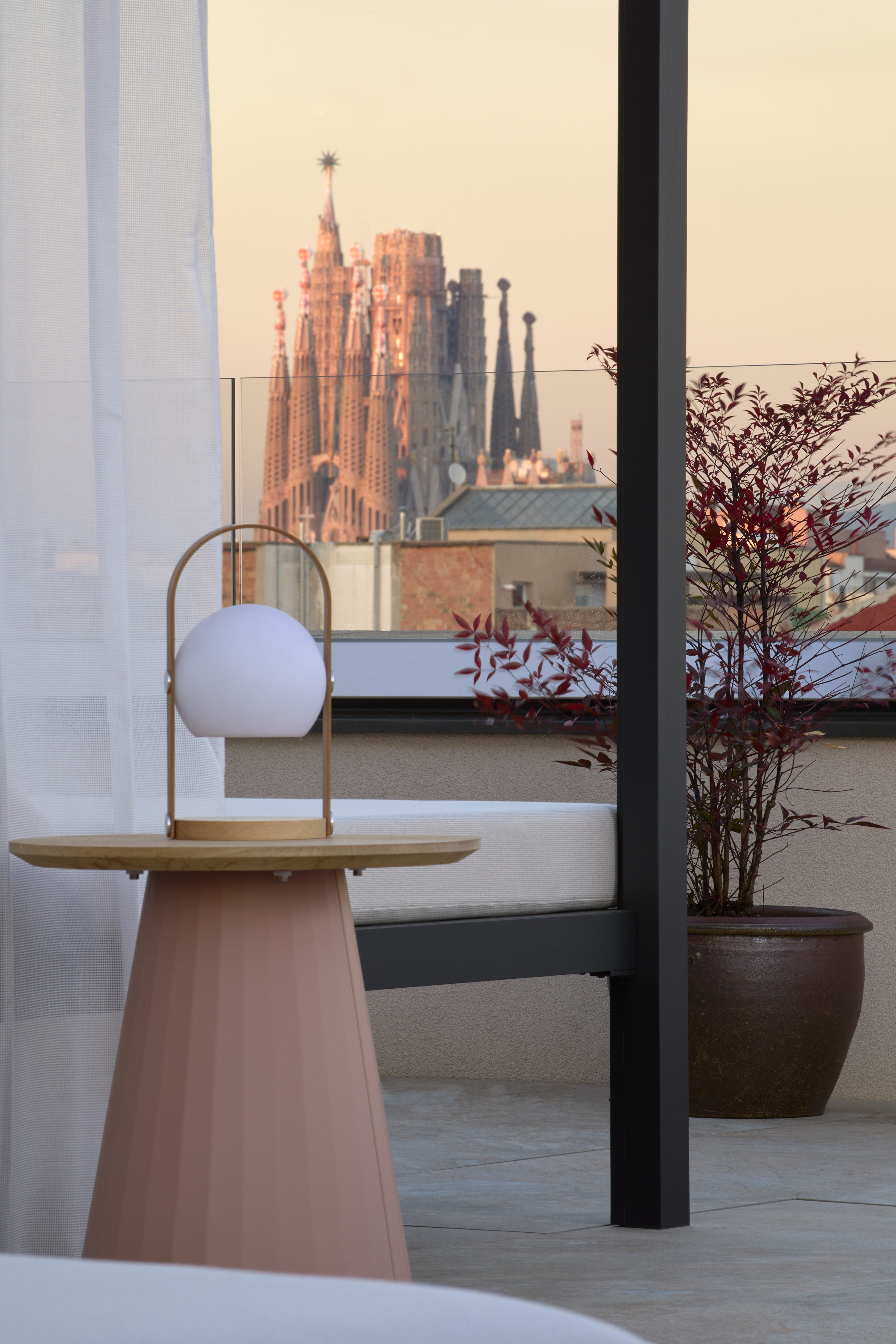 Rooftop terrace with modern lamp, Sagrada Familia view, Barcelona sunset.
