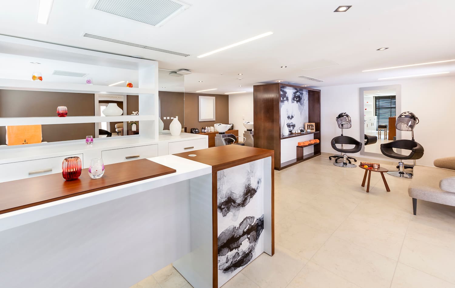 a room with white walls and a white counter with chairs and a wall of shelves
