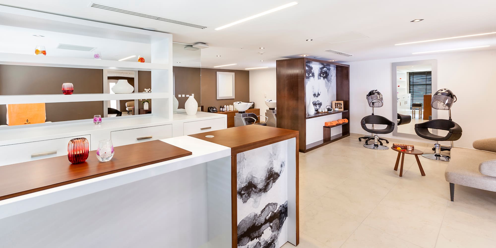 a room with white walls and a white counter with chairs and a wall of shelves