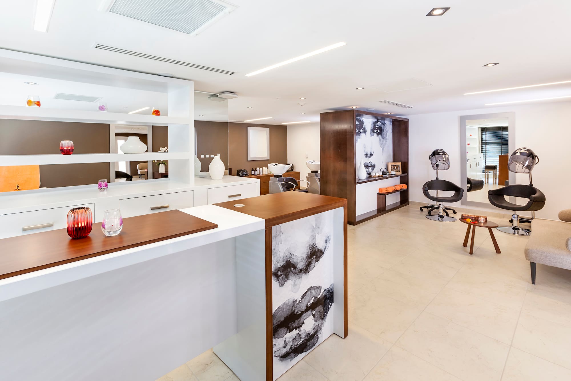 a room with white walls and a white counter with chairs and a wall of shelves