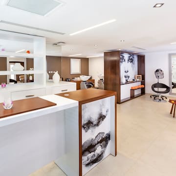 a room with white walls and a white counter with chairs and a wall of shelves