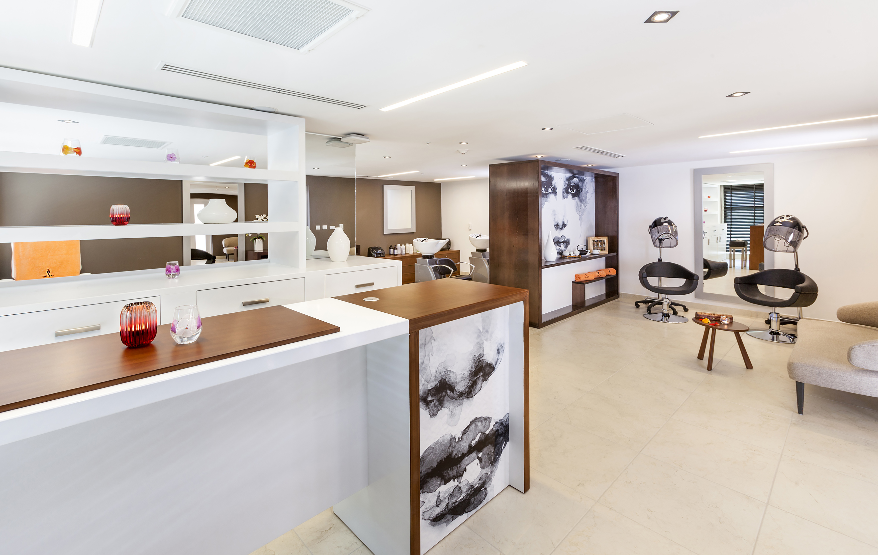 a room with white walls and a white counter with chairs and a wall of shelves