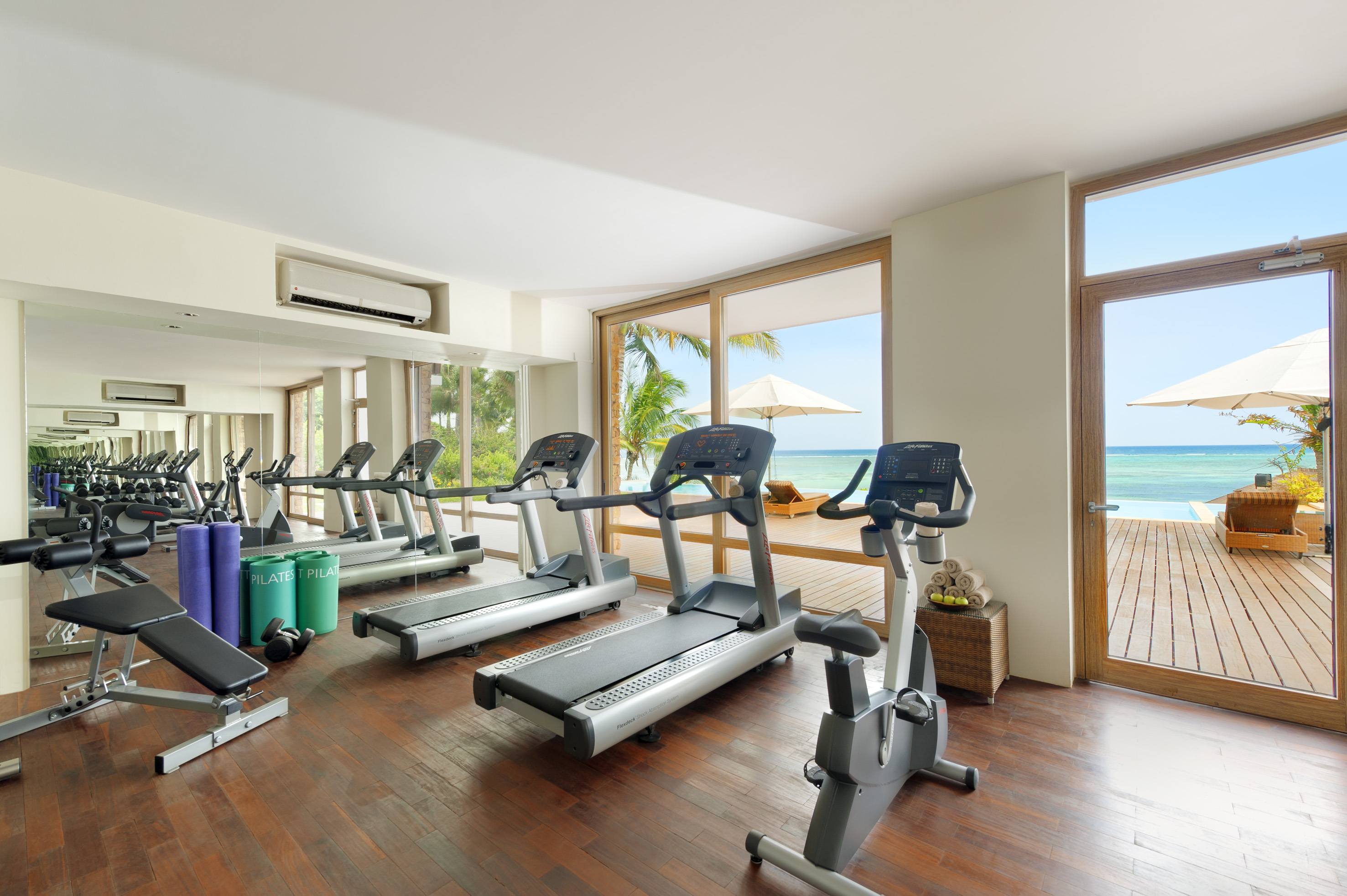 Resort gym with treadmills, exercise bike, weights, and ocean view.