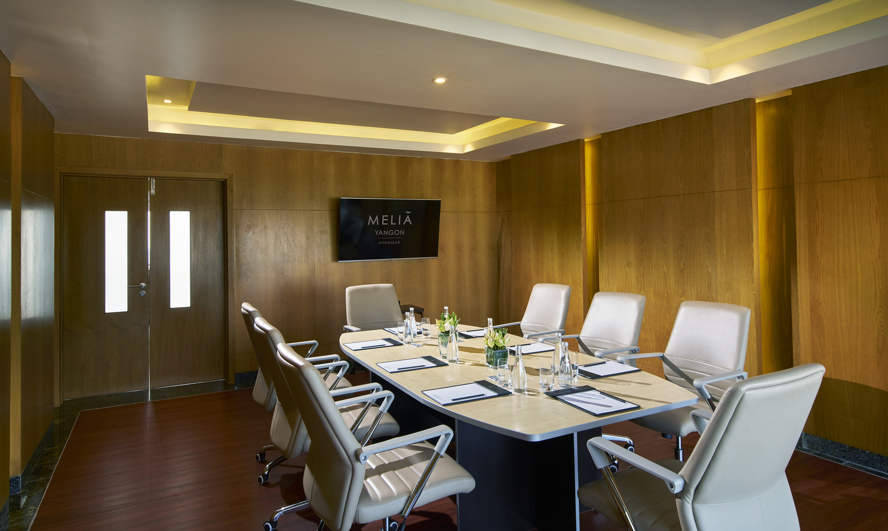 Melia Yangon hotel meeting room with wood paneling and presentation screen.