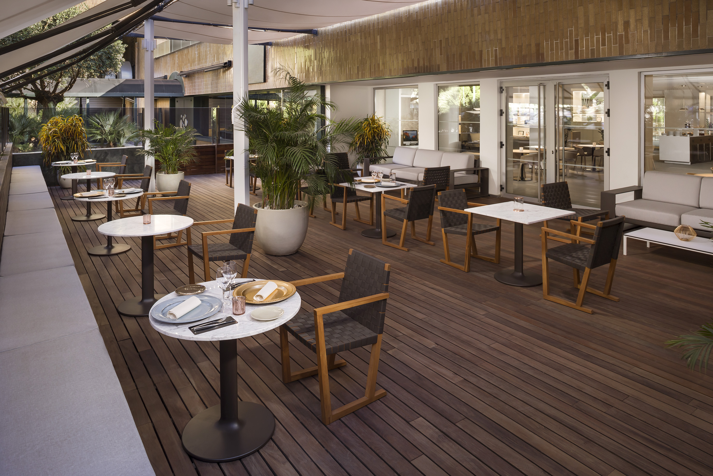 Outdoor restaurant patio with dining and lounge seating on wooden deck.