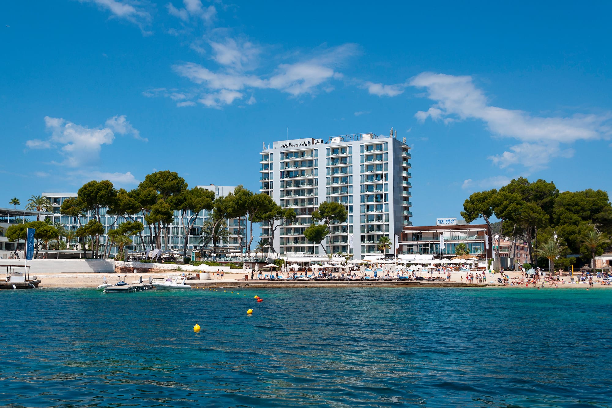 Nikki Beach resort hotel on a sunny beach, modern buildings, blue sea.