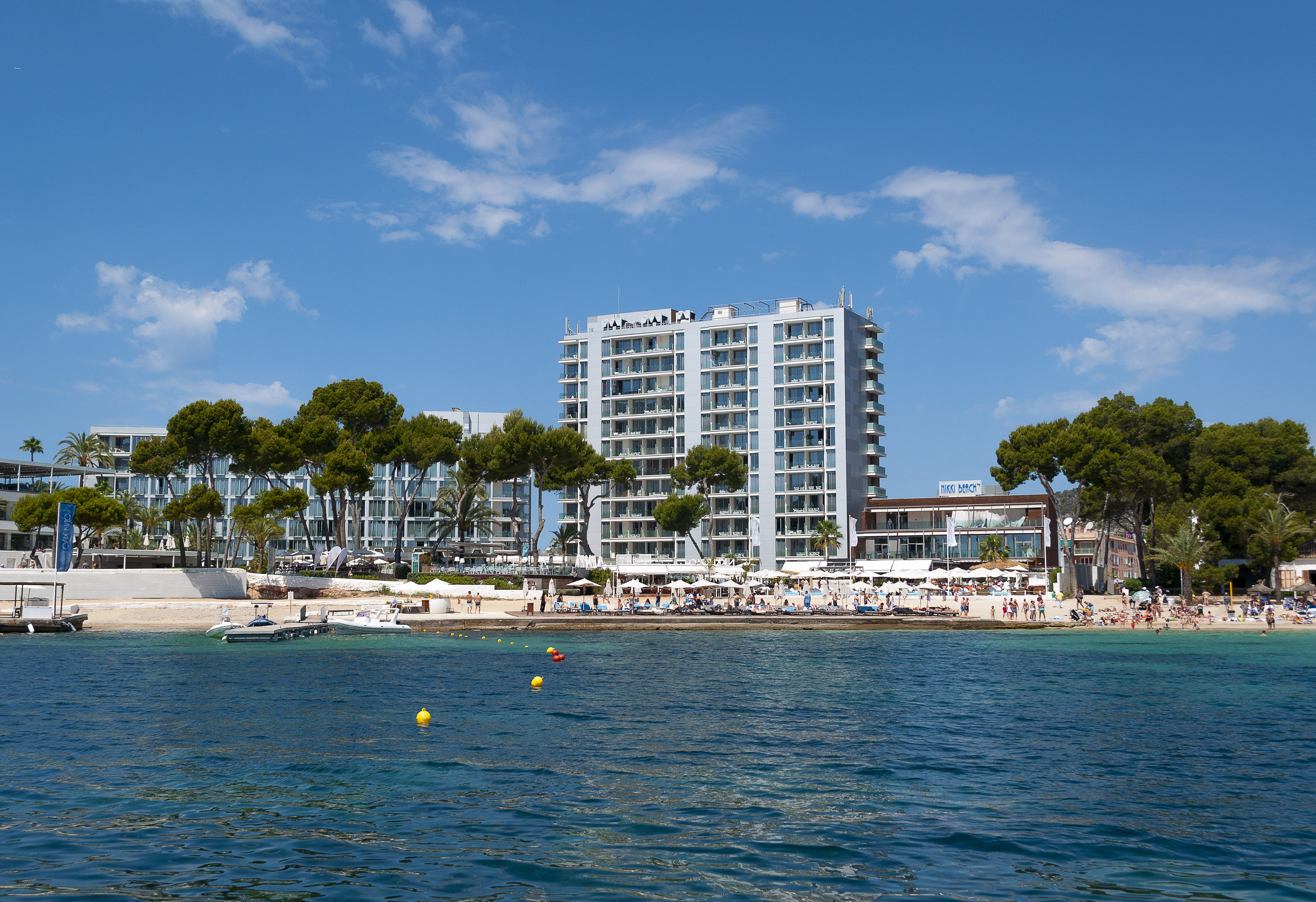 Nikki Beach resort hotel on a sunny beach, modern buildings, blue sea.