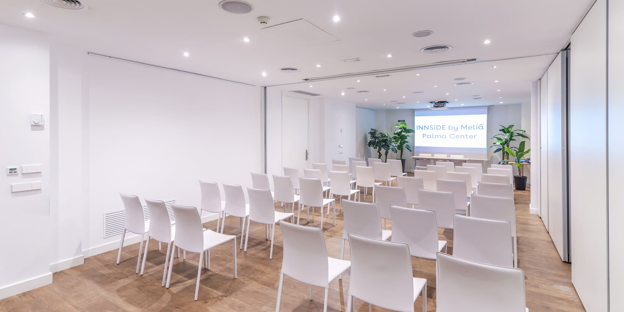 a room with white chairs and a screen