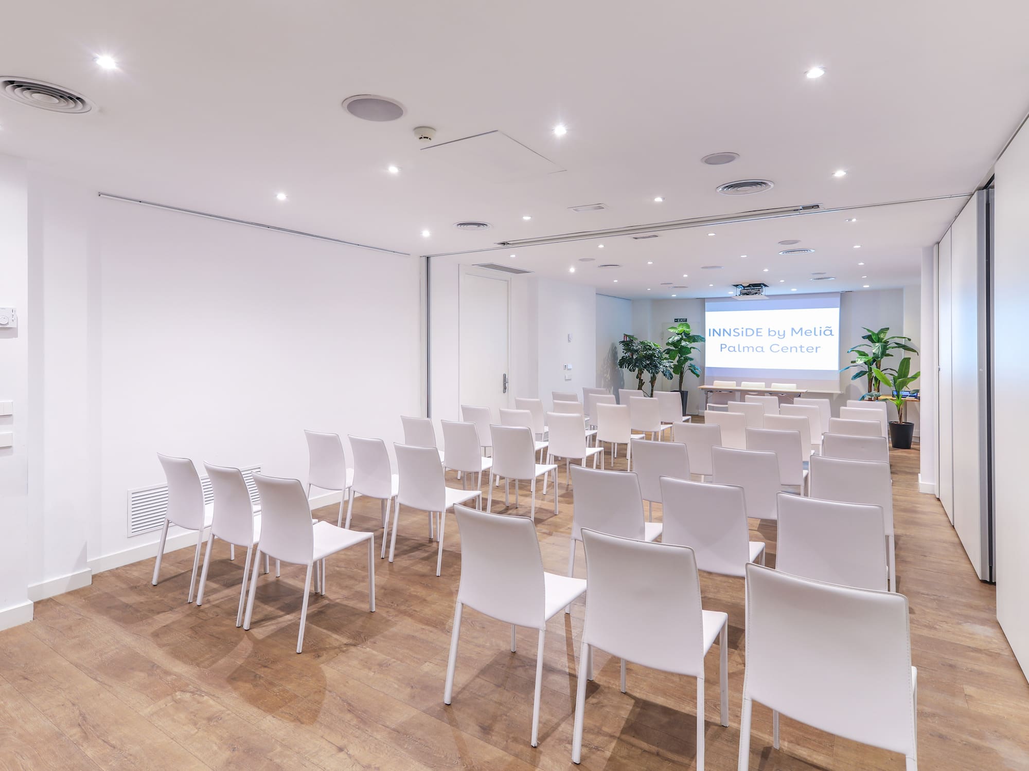 a room with white chairs and a screen