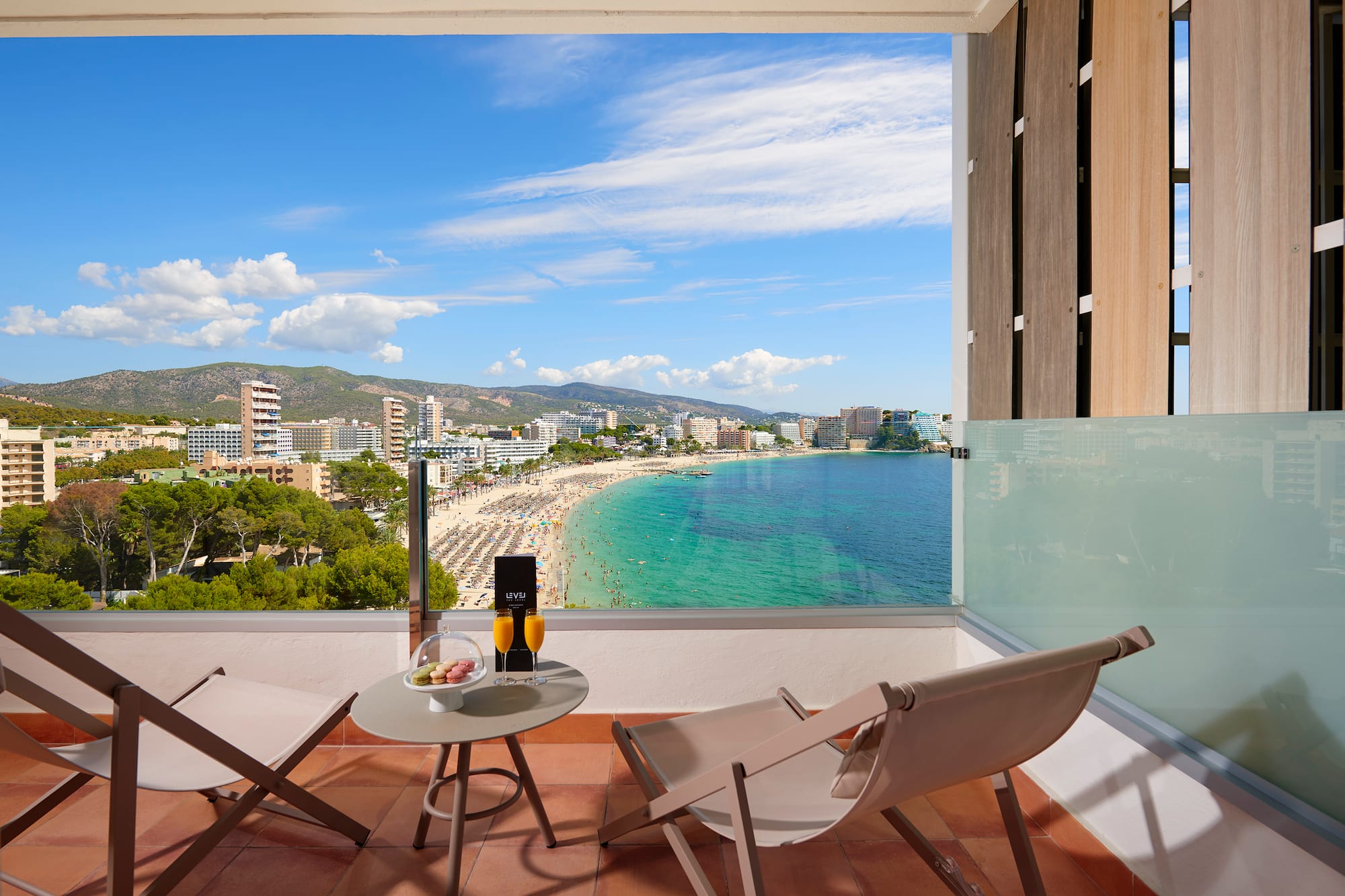 a balcony with chairs and a table overlooking a beach