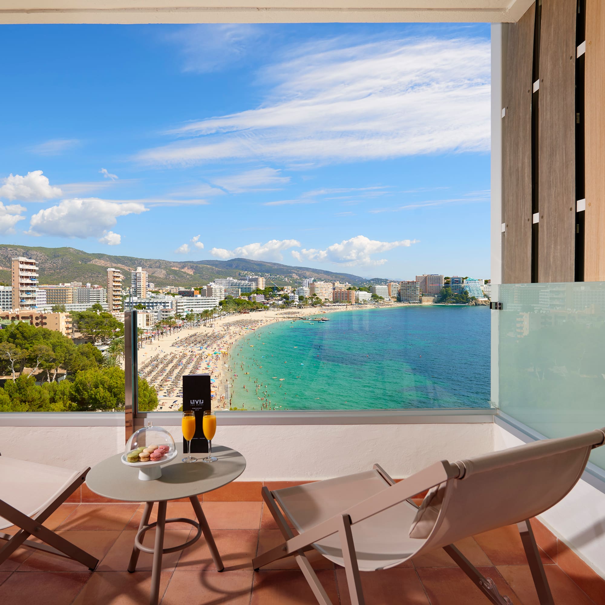a balcony with chairs and a table overlooking a beach