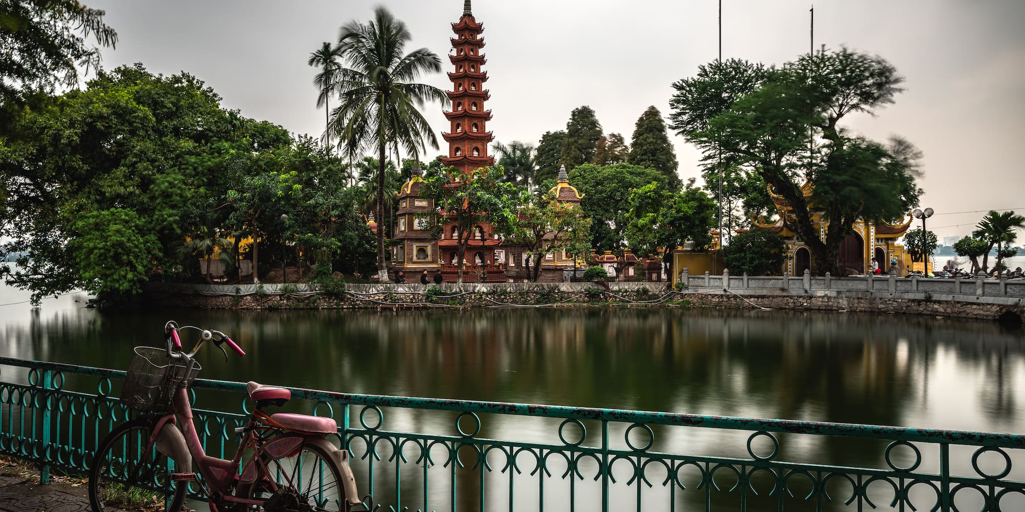 a bicycle parked on a bridge by a body of water