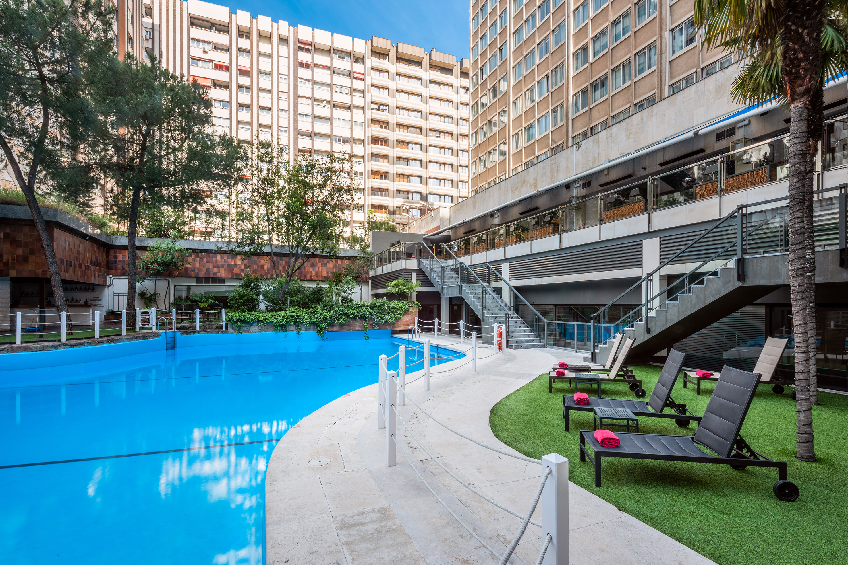 a swimming pool with chairs and a building in the background