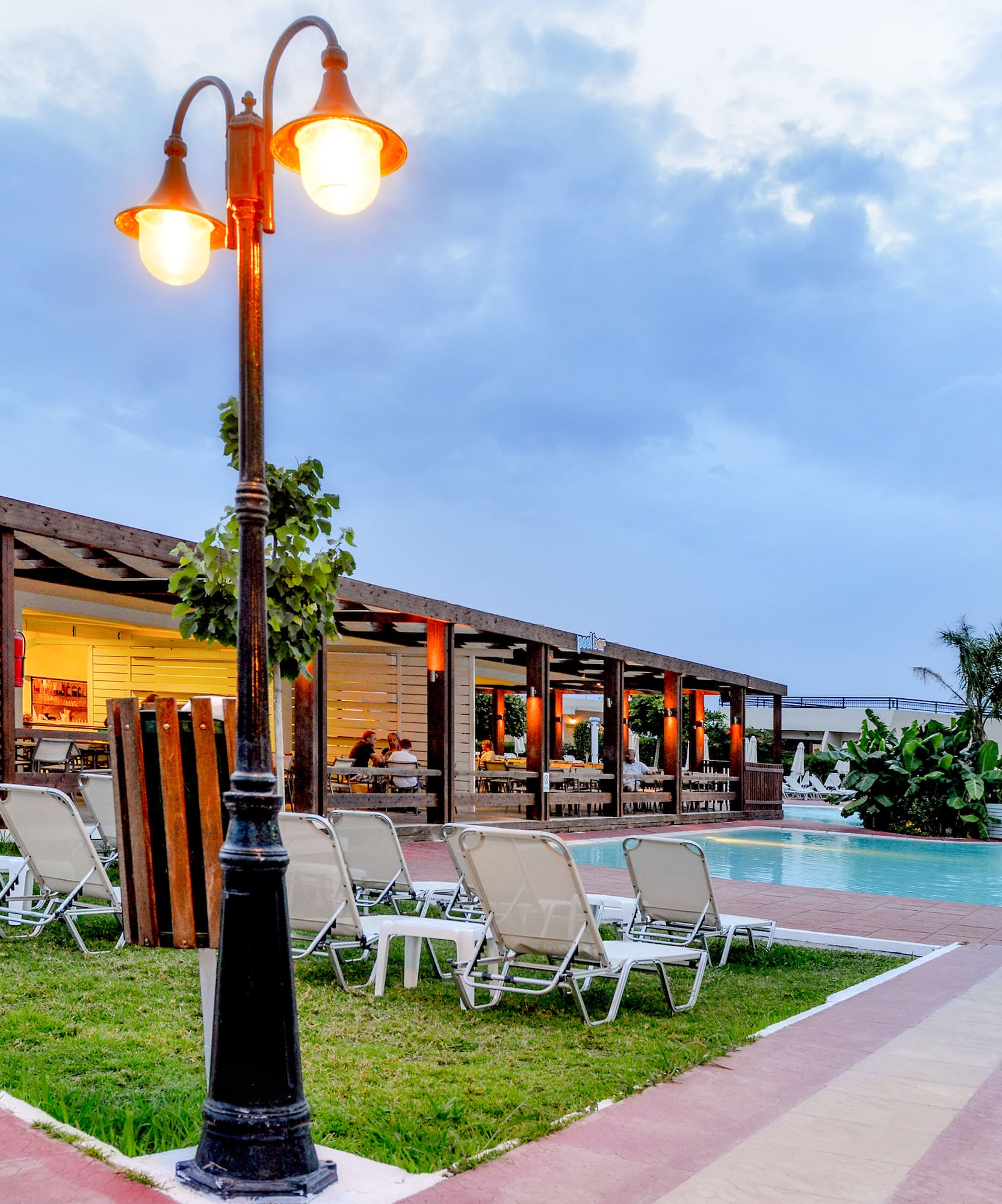 a pool with a light post and lawn chairs