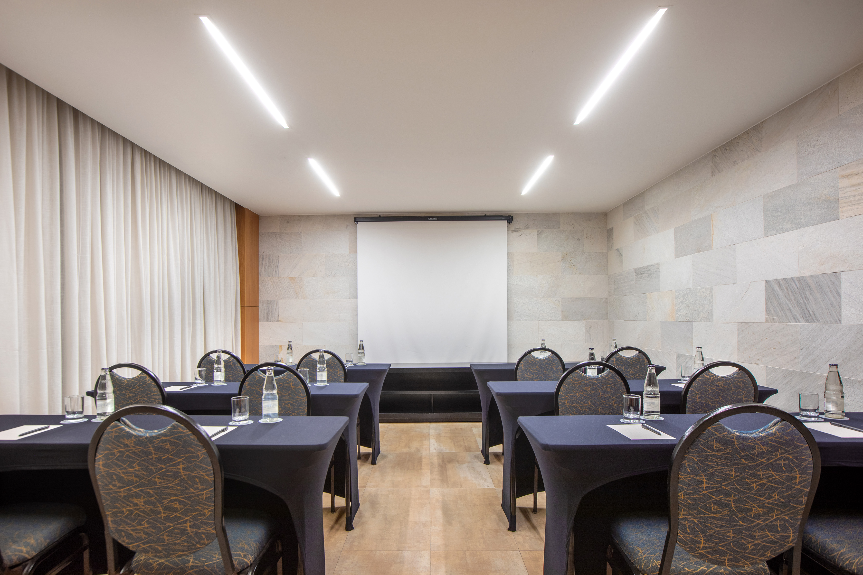 Empty corporate meeting room with projection screen, tables, and chairs.