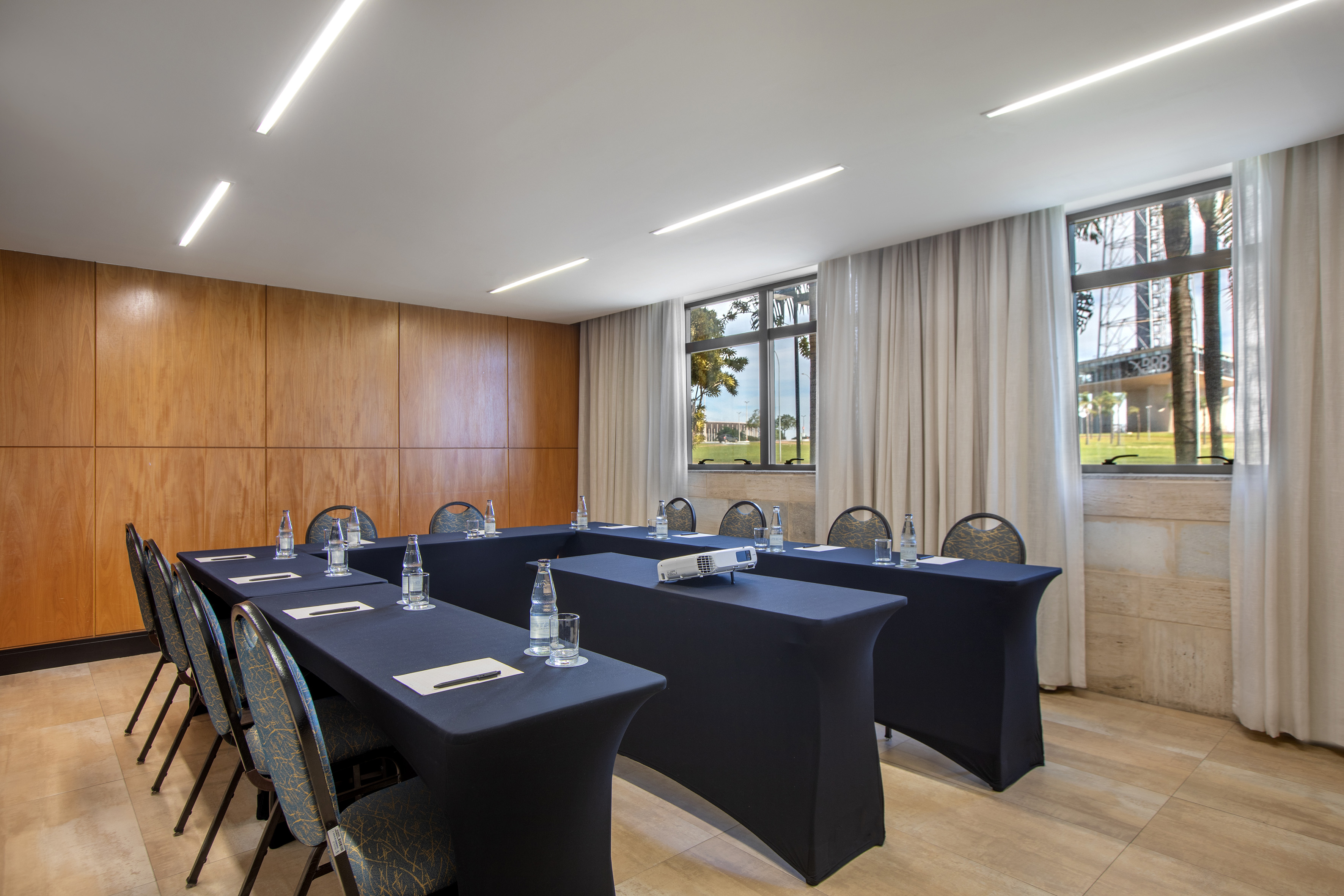 Modern corporate meeting room with U-table setup, projector, and large windows.