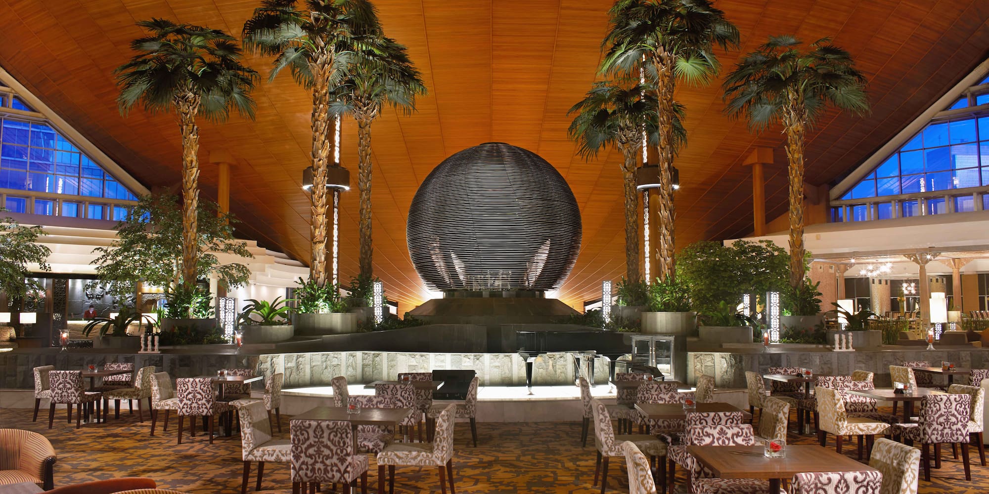 a room with tables and chairs and palm trees