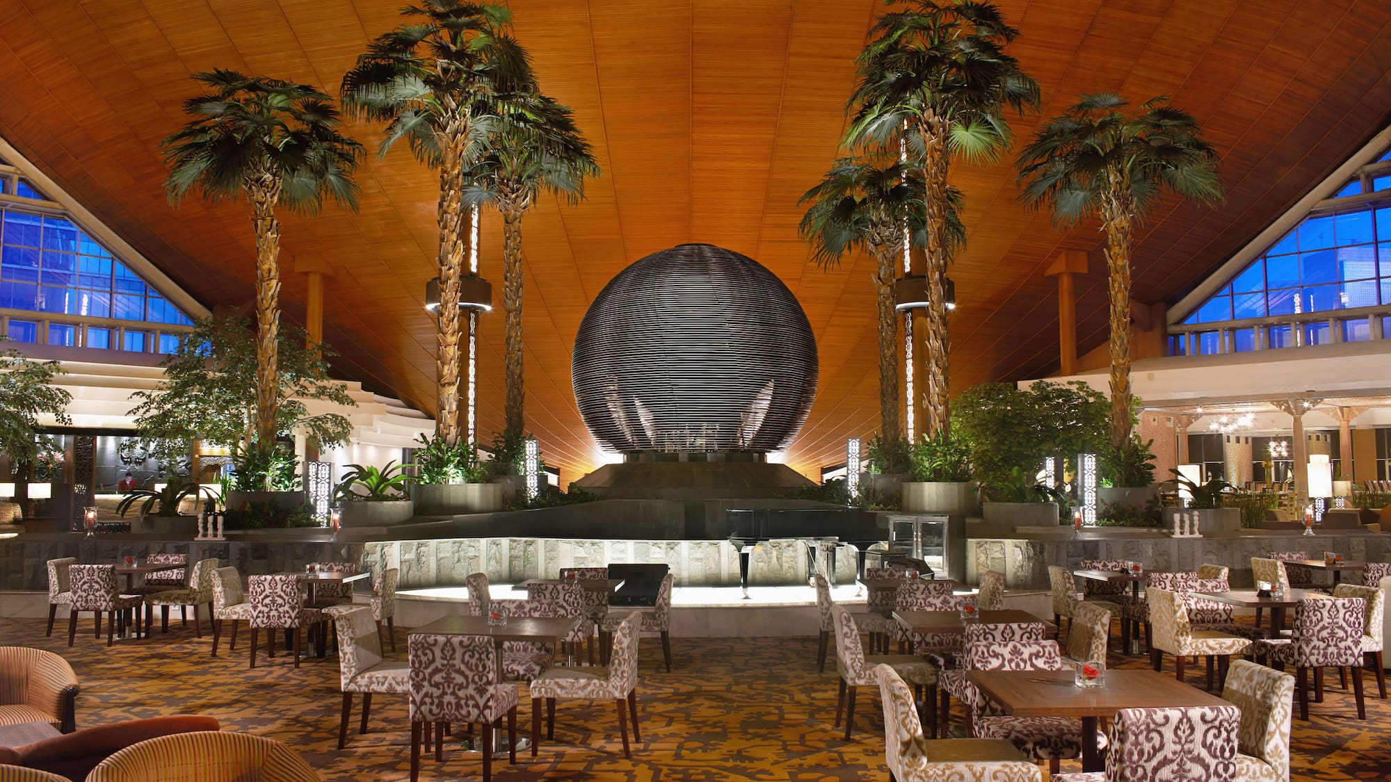 a room with tables and chairs and palm trees