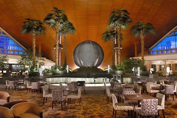 a room with tables and chairs and palm trees