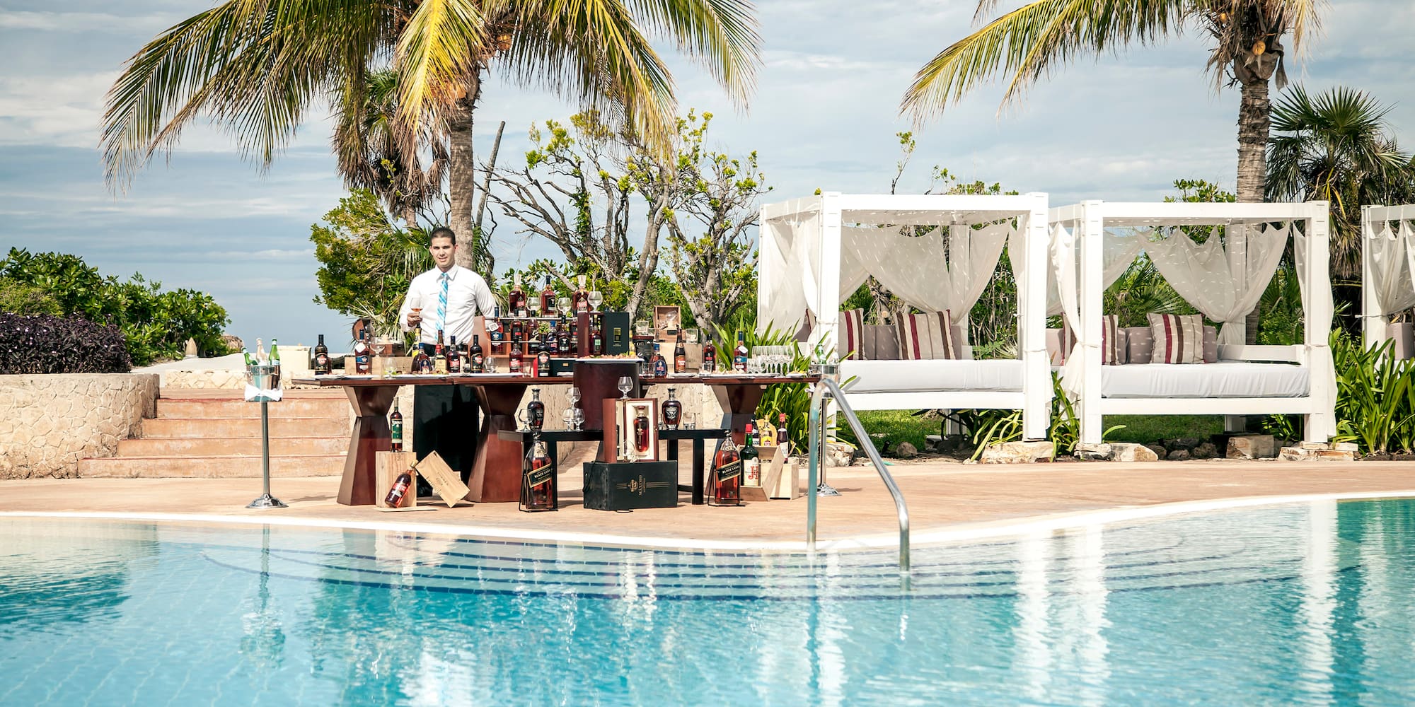 a man standing at a table with a bar in front of a pool