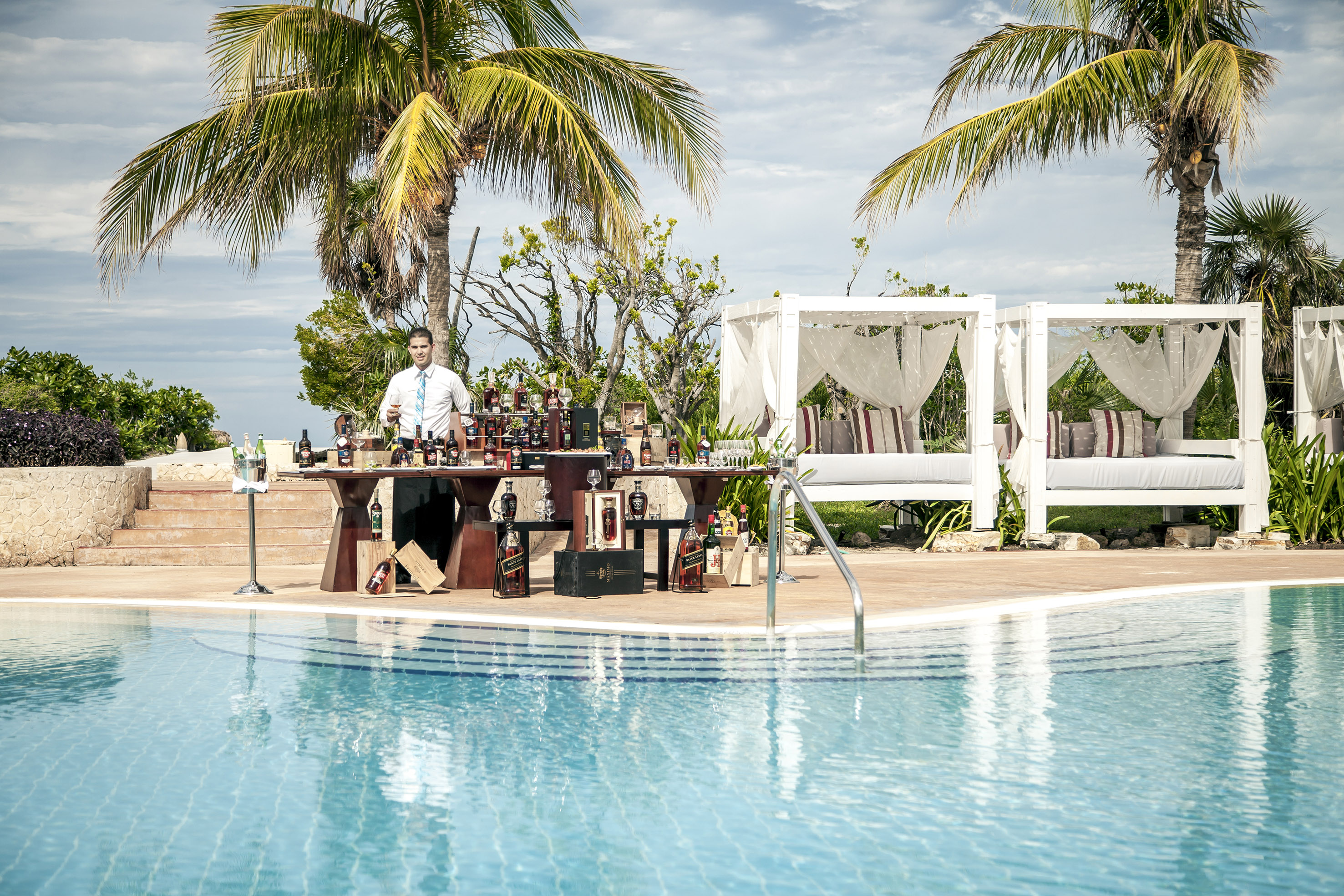 a man standing at a table with a bar in front of a pool