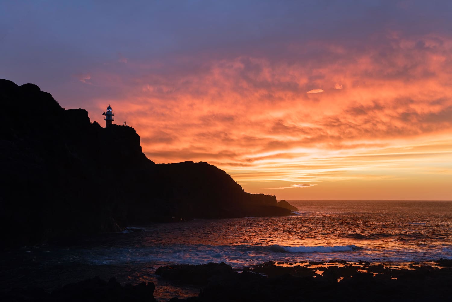 a sunset over a rocky beach