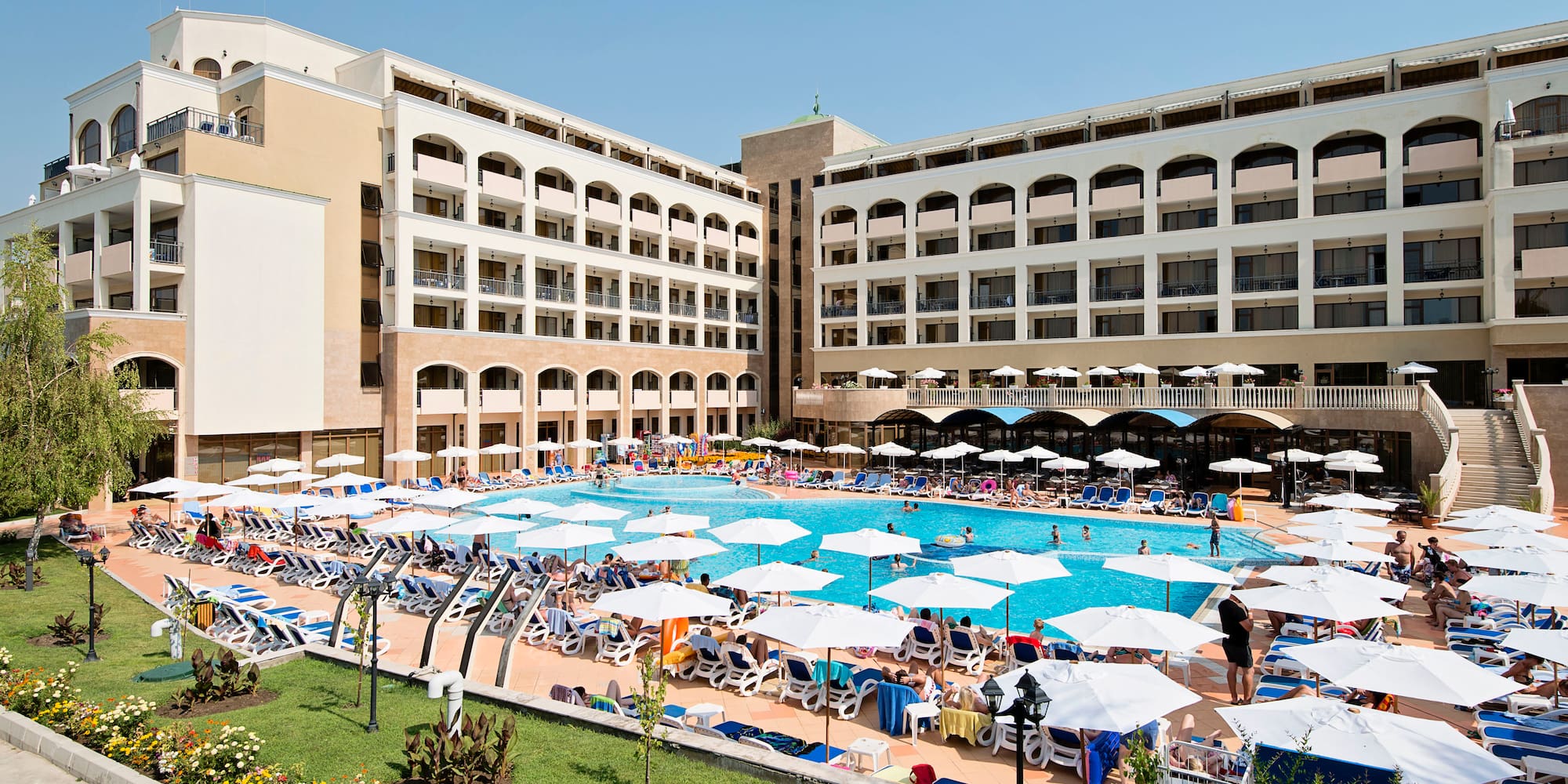 a large pool with umbrellas and chairs in front of a building
