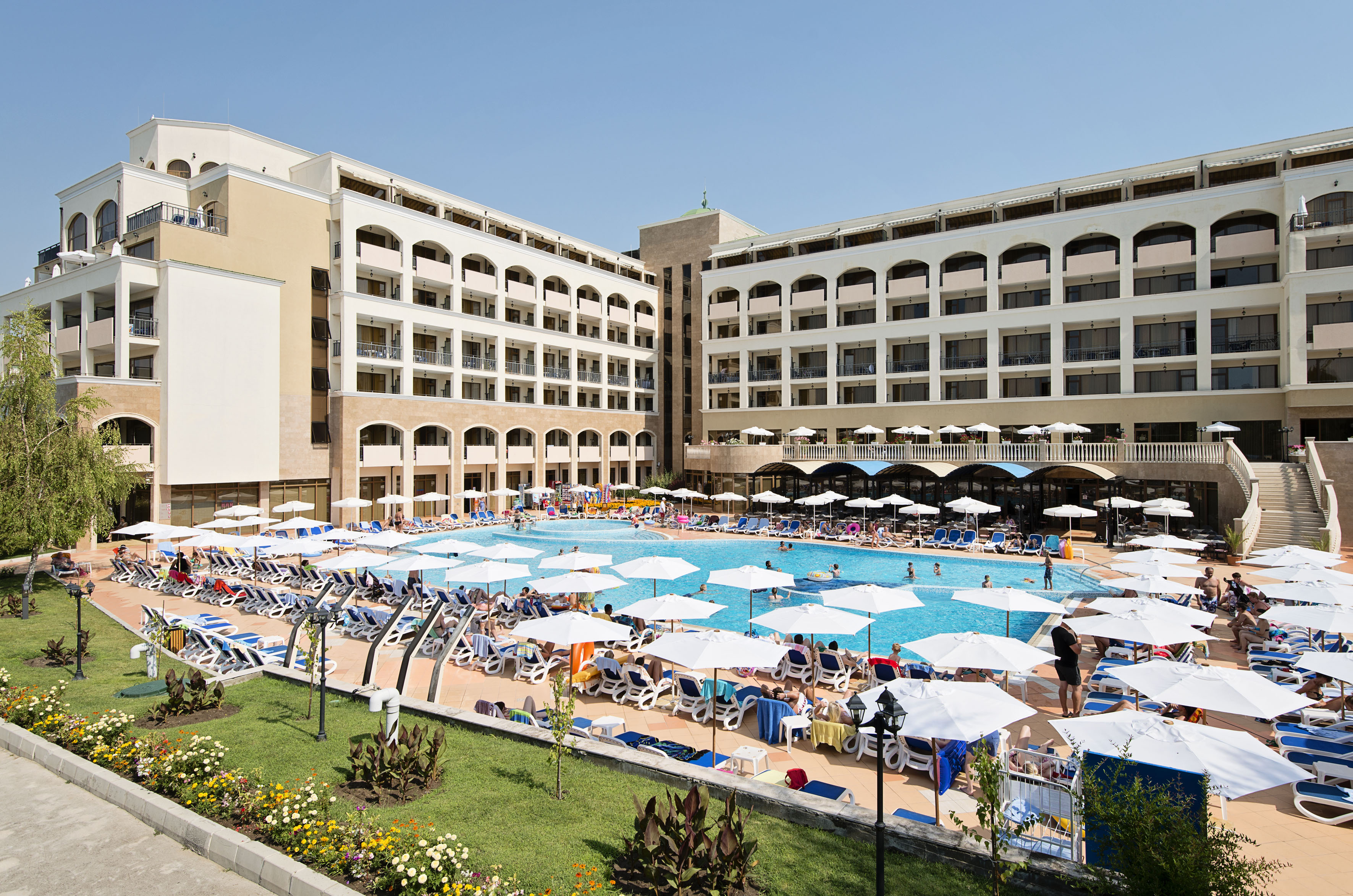 a large pool with umbrellas and chairs in front of a building