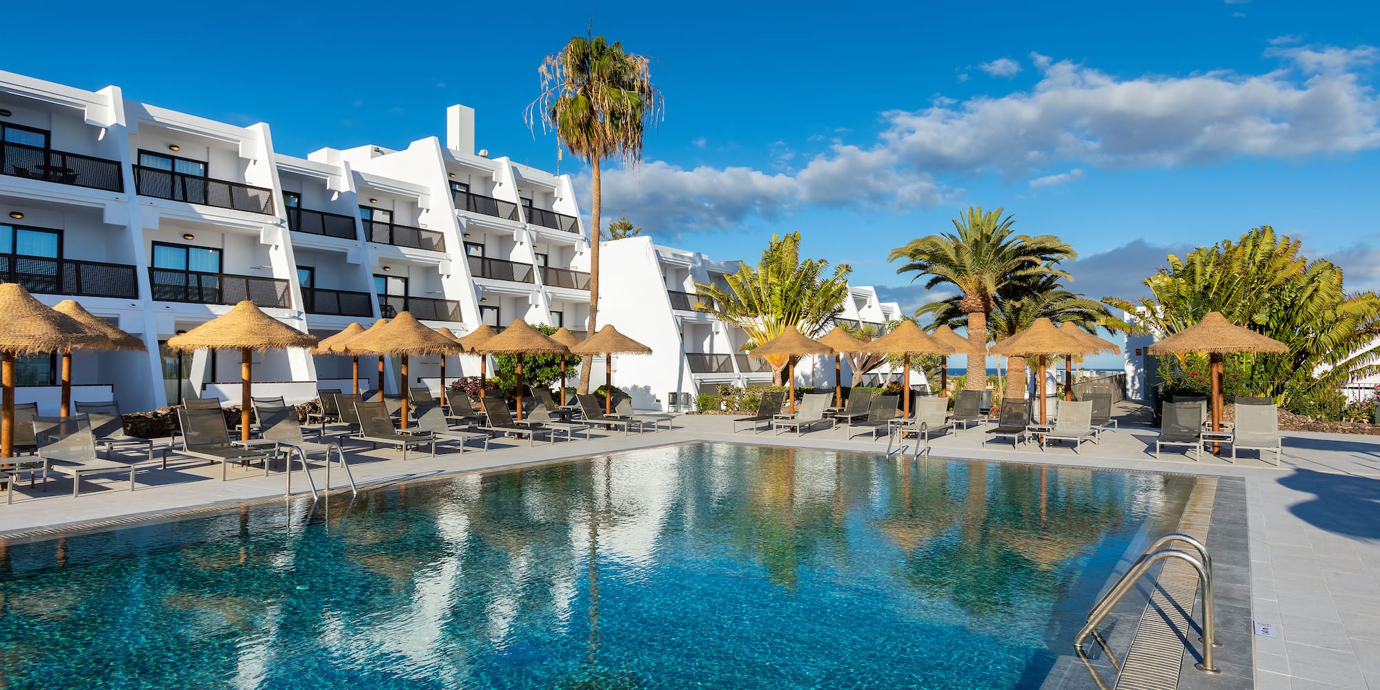 a pool with umbrellas and chairs in front of a building