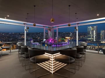 a bar with chairs and a view of a city