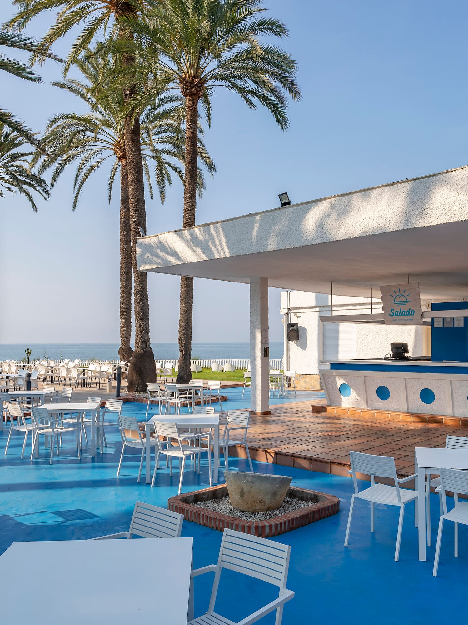 a white tables and chairs on a blue surface with palm trees