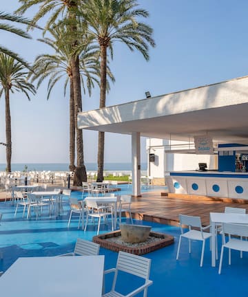 a white tables and chairs on a blue surface with palm trees