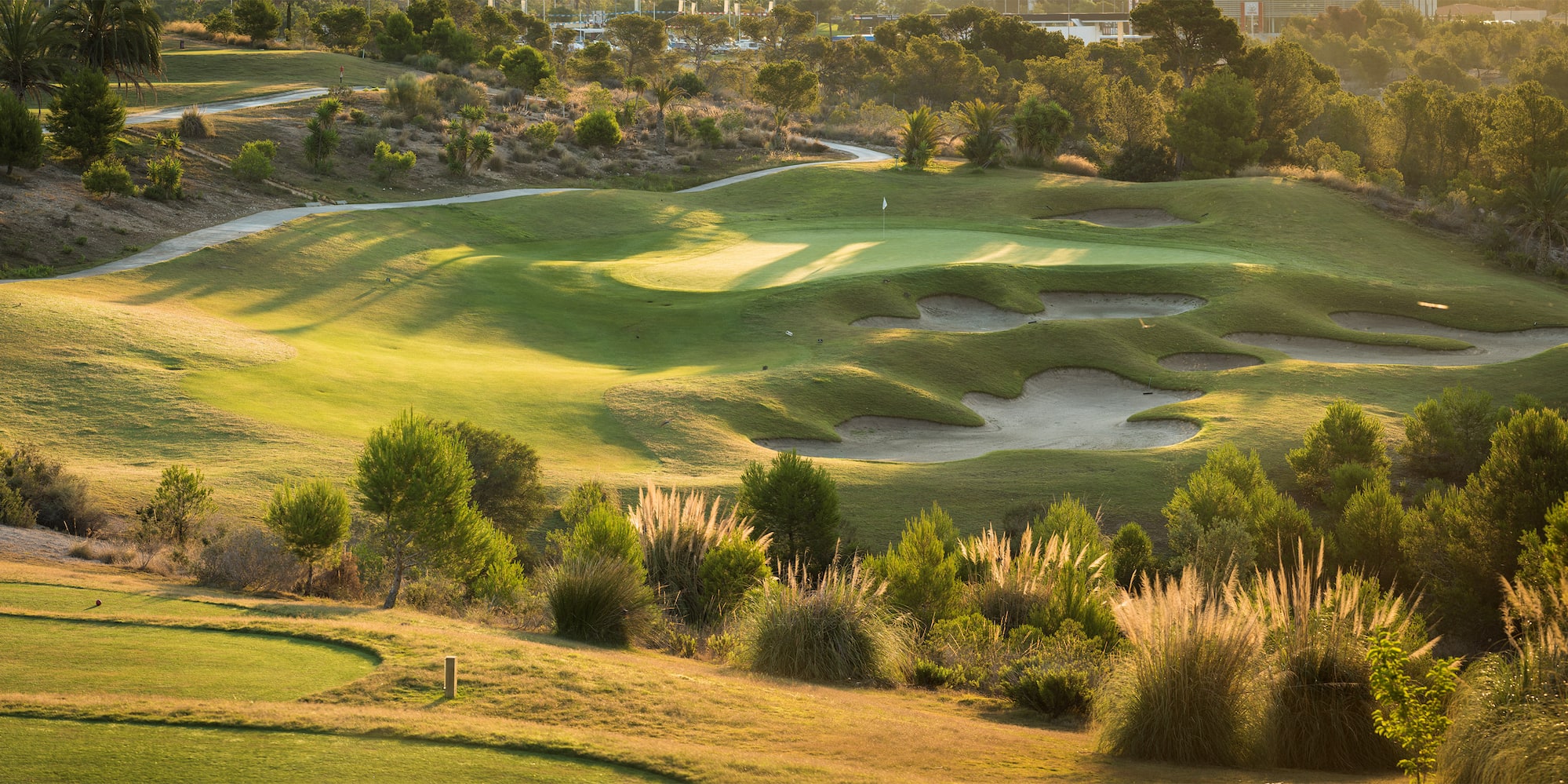 a golf course with sand bunkers and trees