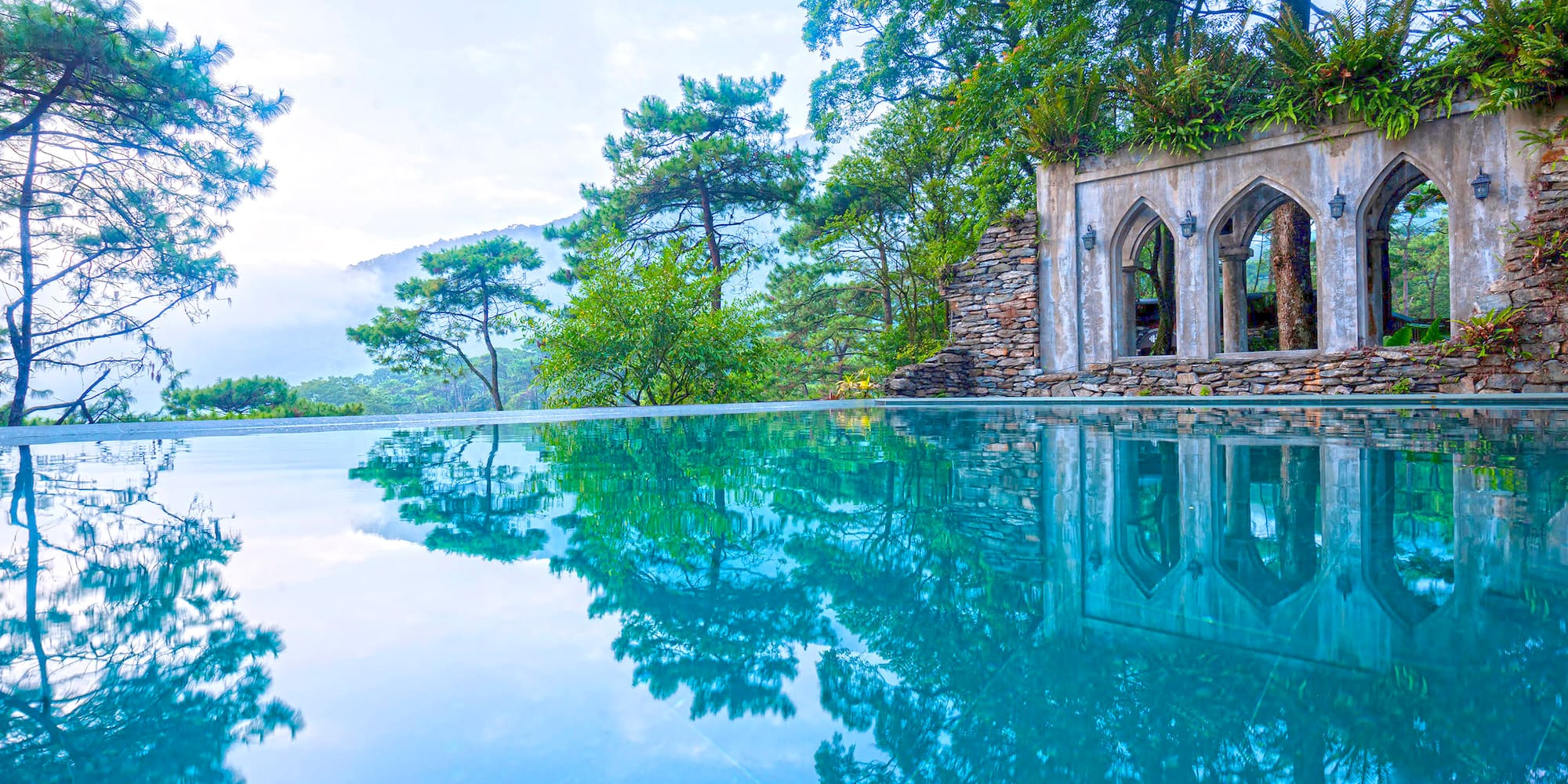 a pool with trees and a stone structure