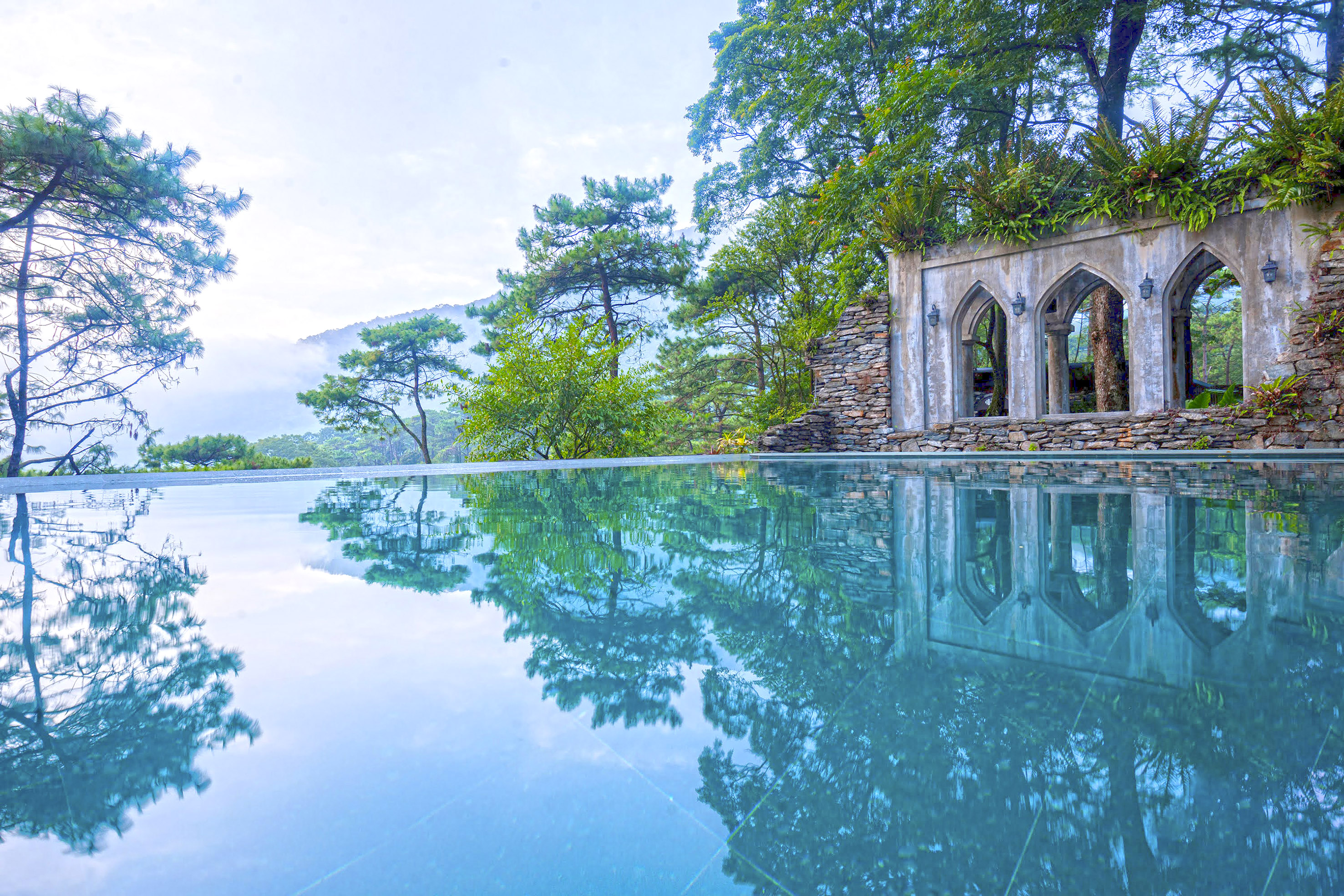 a pool with trees and a stone structure