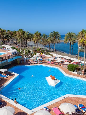 a pool with umbrellas and chairs and palm trees